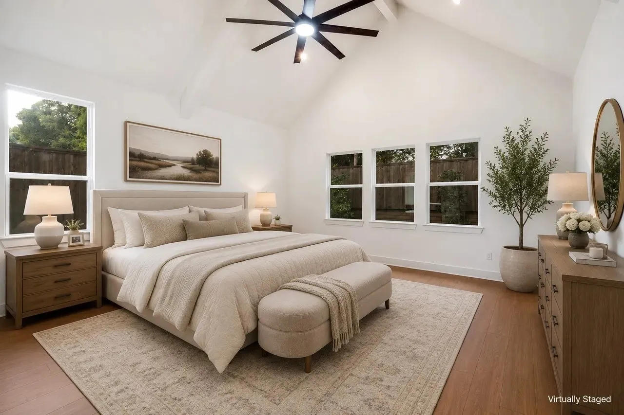 Vaulted ceiling with an attached ceiling fan, multiple large windows, and wood-finish flooring