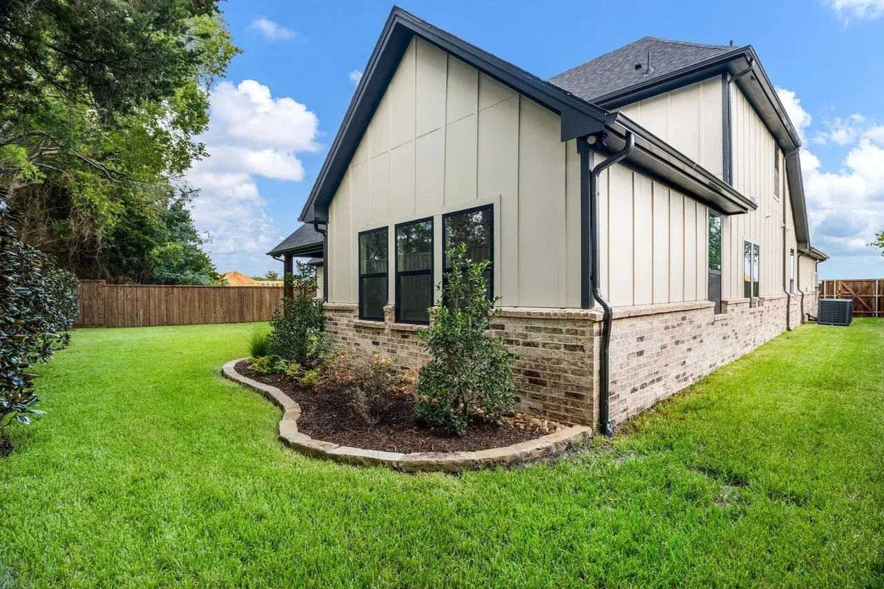 Exterior featuring brick and board-and-batten siding with black-framed windows