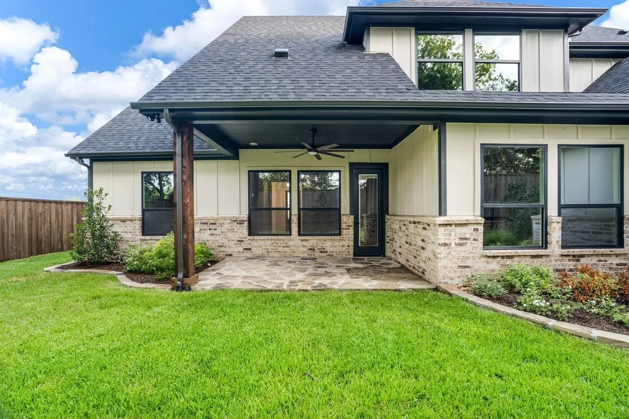 Outdoor covered patio with ceiling fan, flagstone paving, and brick and vertical siding exterior