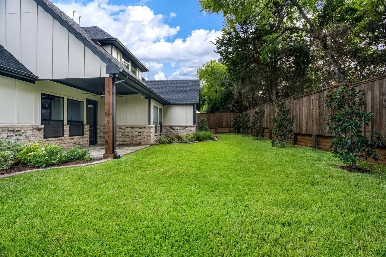 Expansive green lawn with a wood privacy fence and mature trees