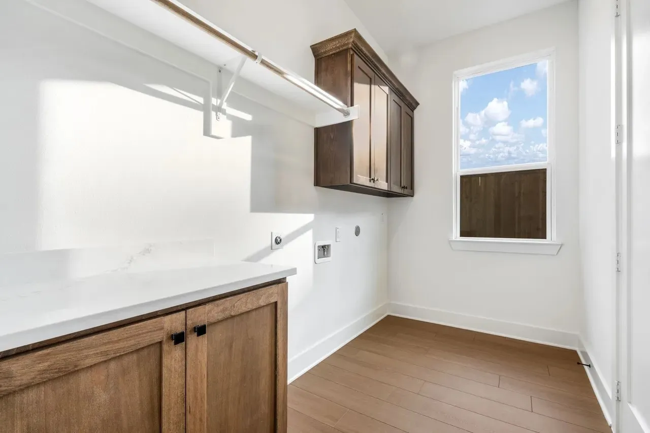 Utility room with wood-finish flooring, white walls, and a window