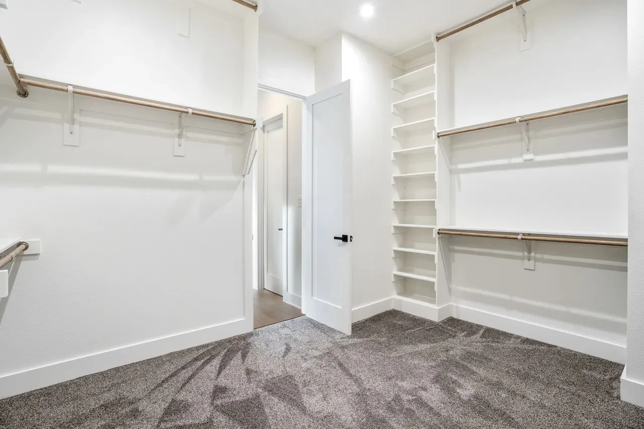 Walk-in closet with ample hanging rods, built-in shelving, and carpet flooring