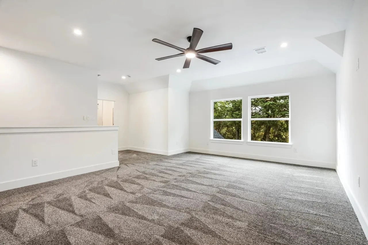 Recessed lighting, ceiling fan with integrated light, two windows, patterned carpeting, and white wall finishes