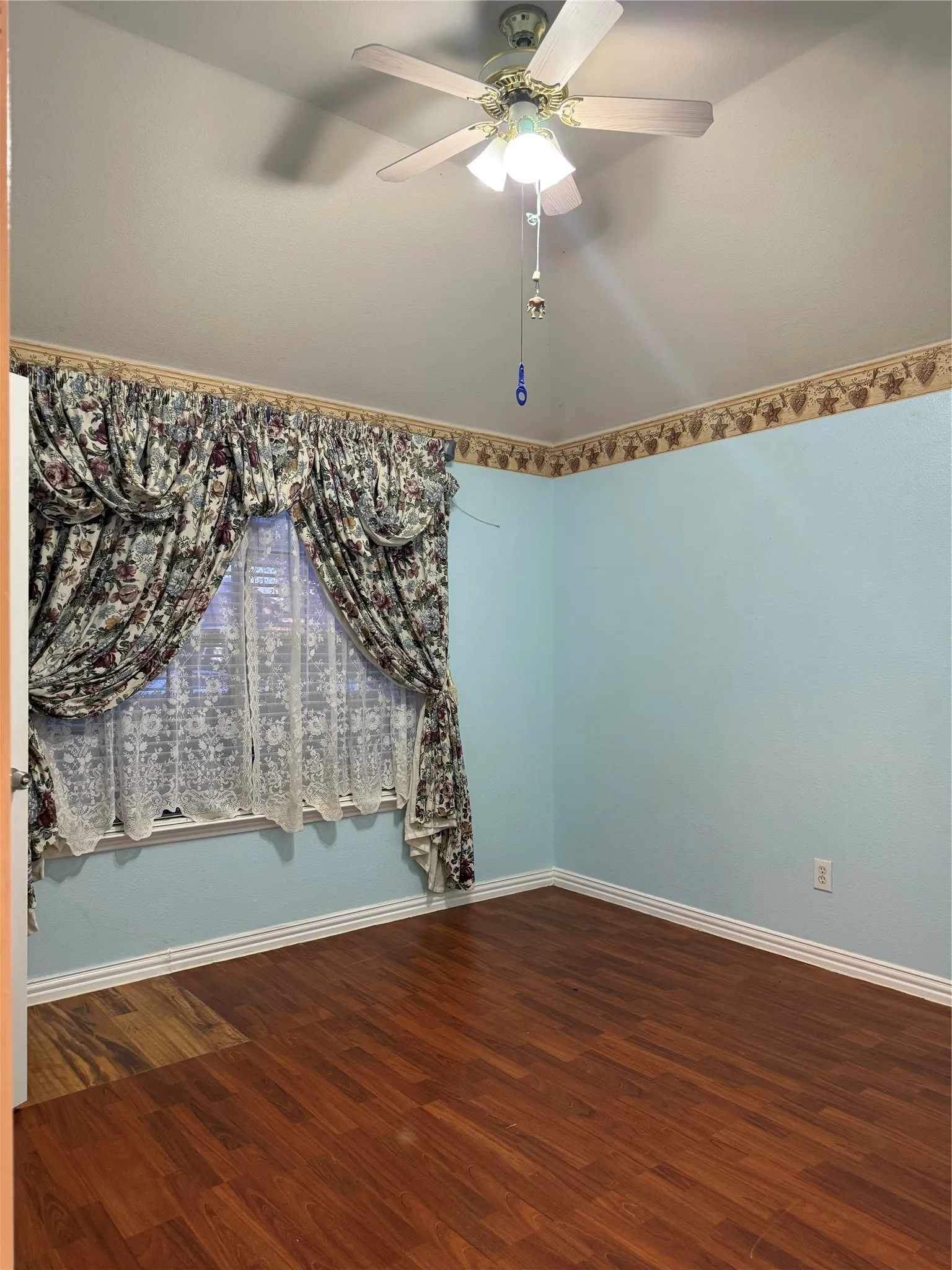 Wood-finish flooring with white trim and a ceiling fan with integrated lighting