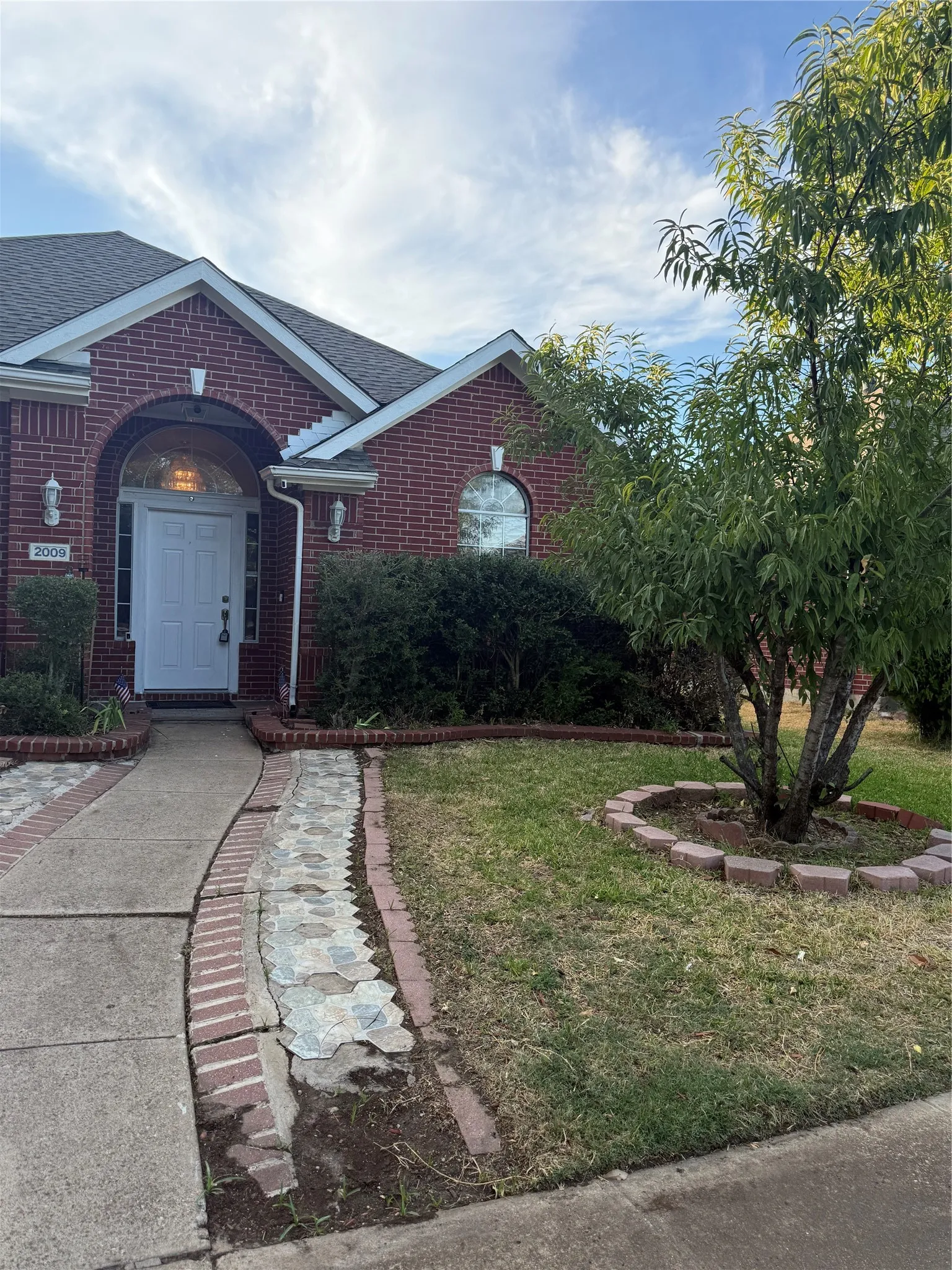 Red brick exterior with white trim, arched entryway, and front door with decorative glass