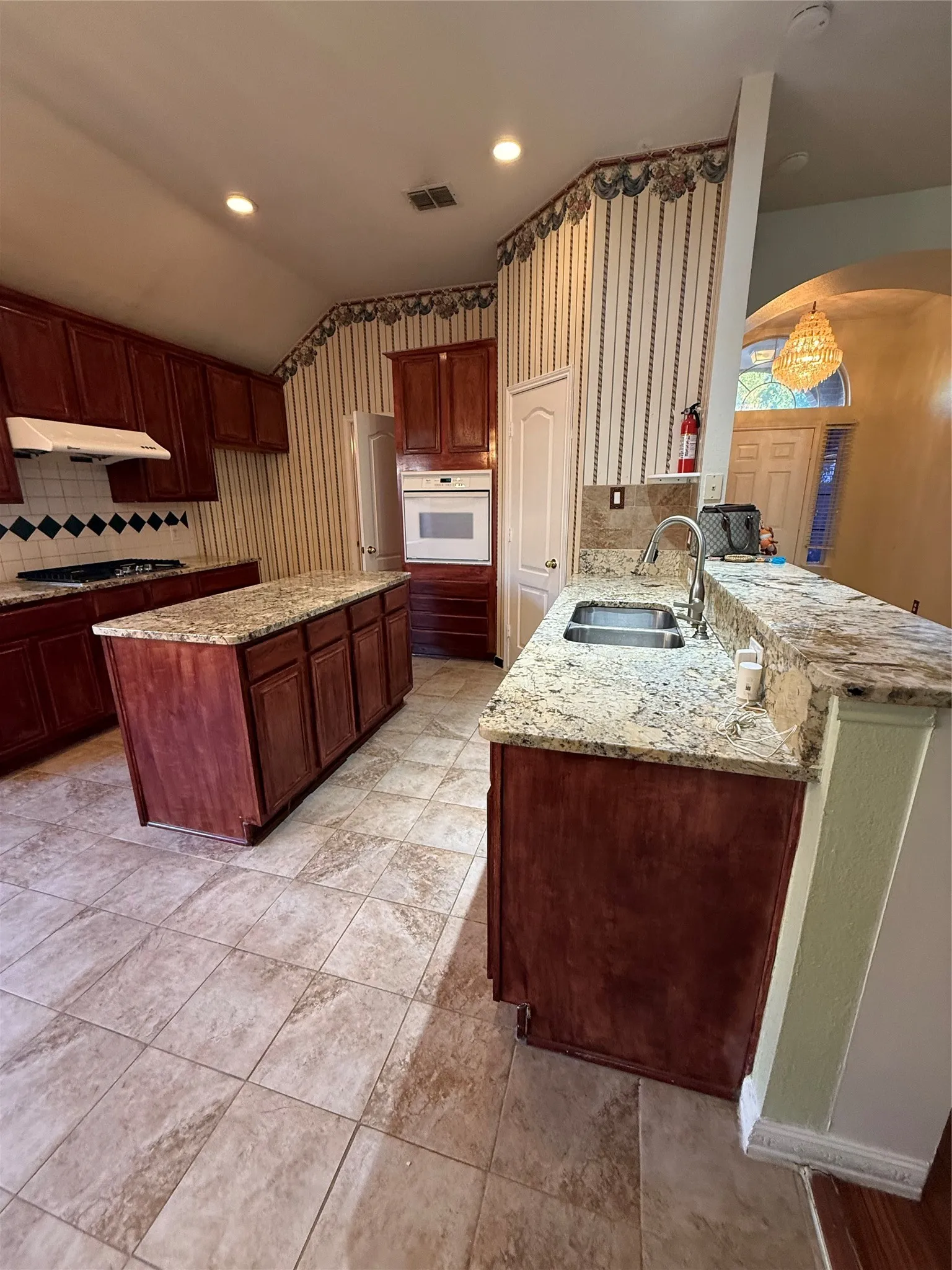 Kitchen featuring wood-finish cabinetry, tile flooring, granite countertops, and recessed lighting