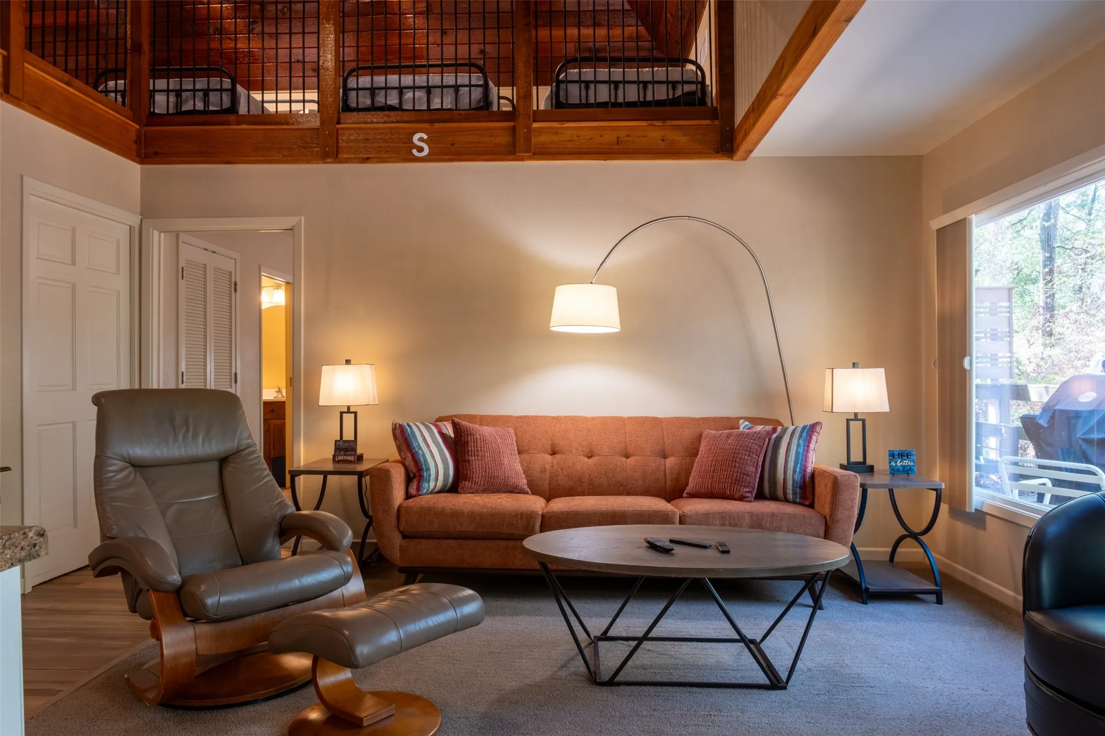 Vaulted ceiling with exposed wood beams, wood-finish flooring, interior window, and a light-filled window
