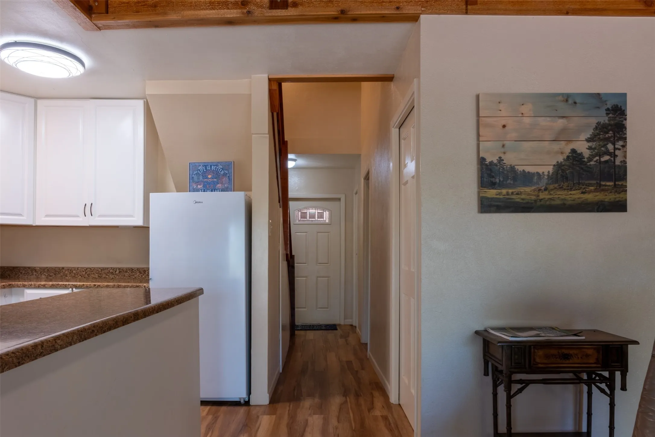 Kitchen area featuring white cabinetry, a speckled countertop, and wood-finish flooring