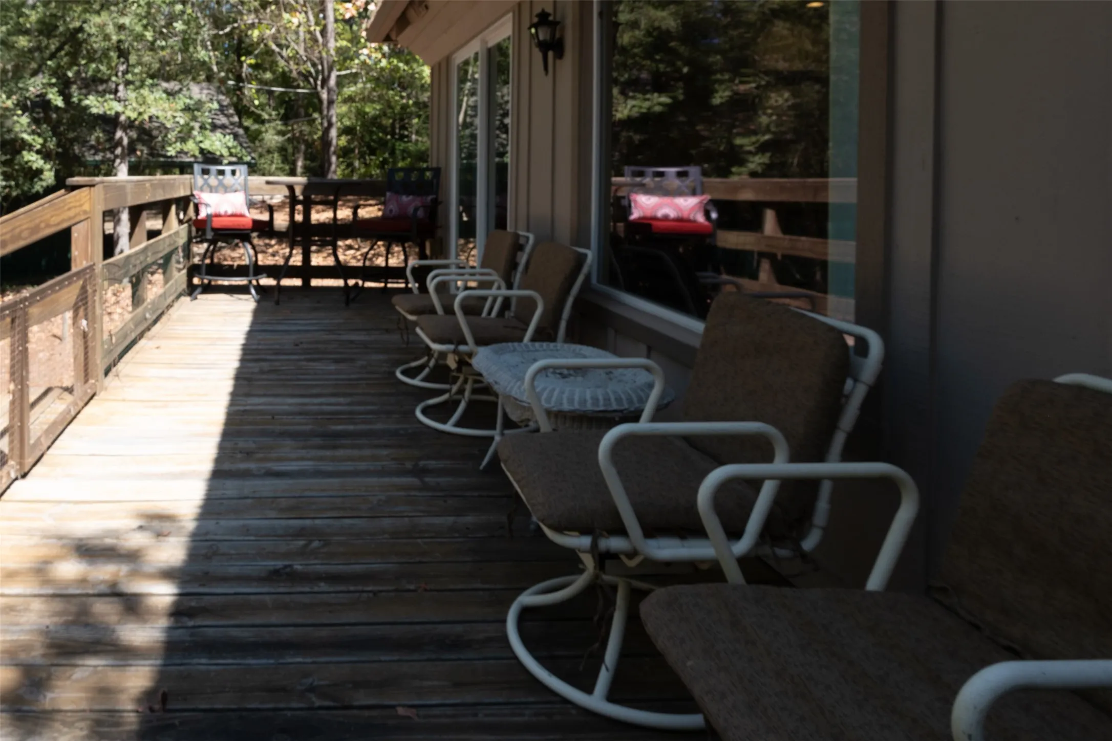 Expansive wood deck with a wood railing and panel siding, featuring large sliding glass doors