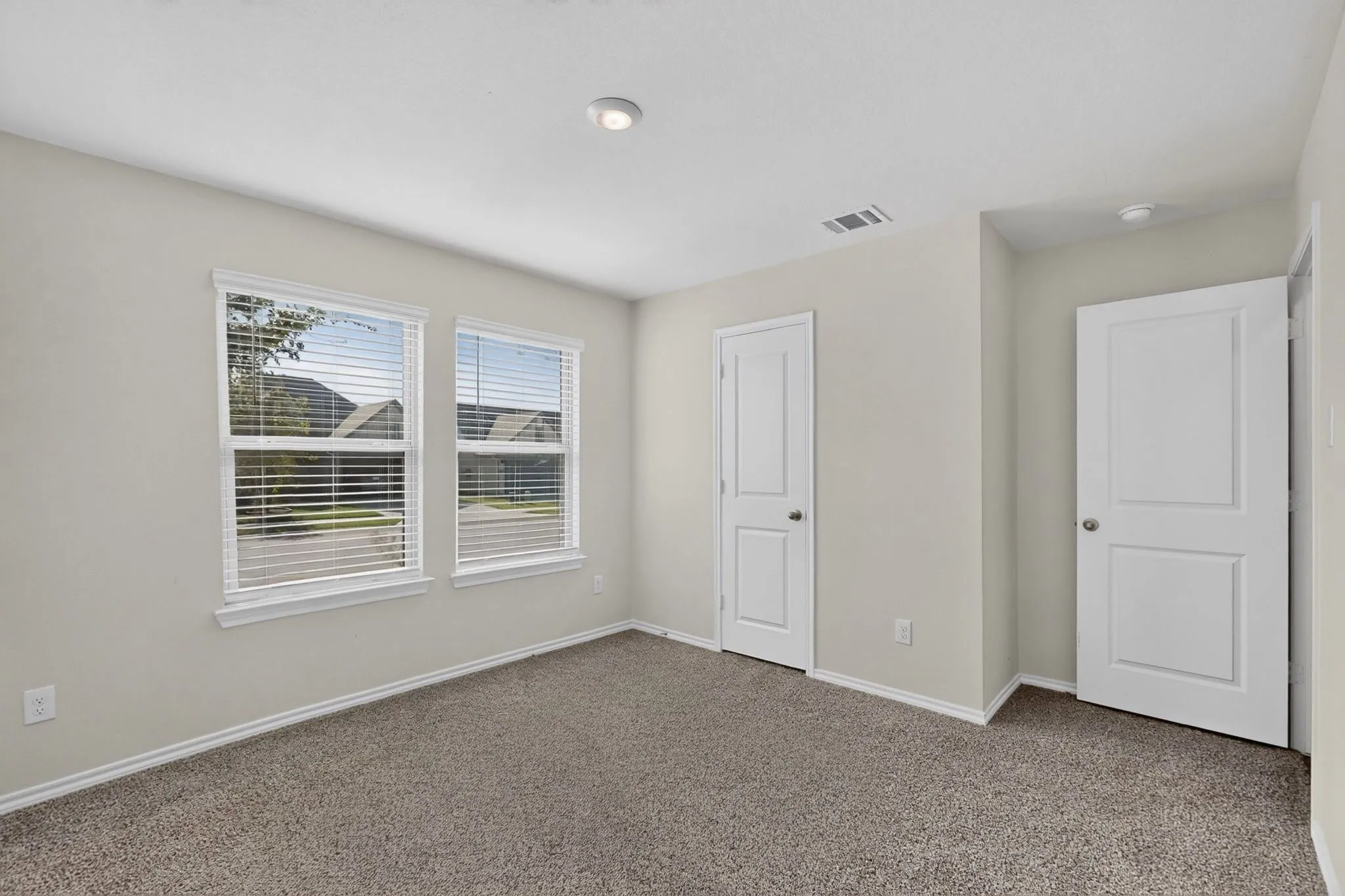 Wall-to-wall carpeting, dual windows with blinds, recessed ceiling lighting, and two panel doors