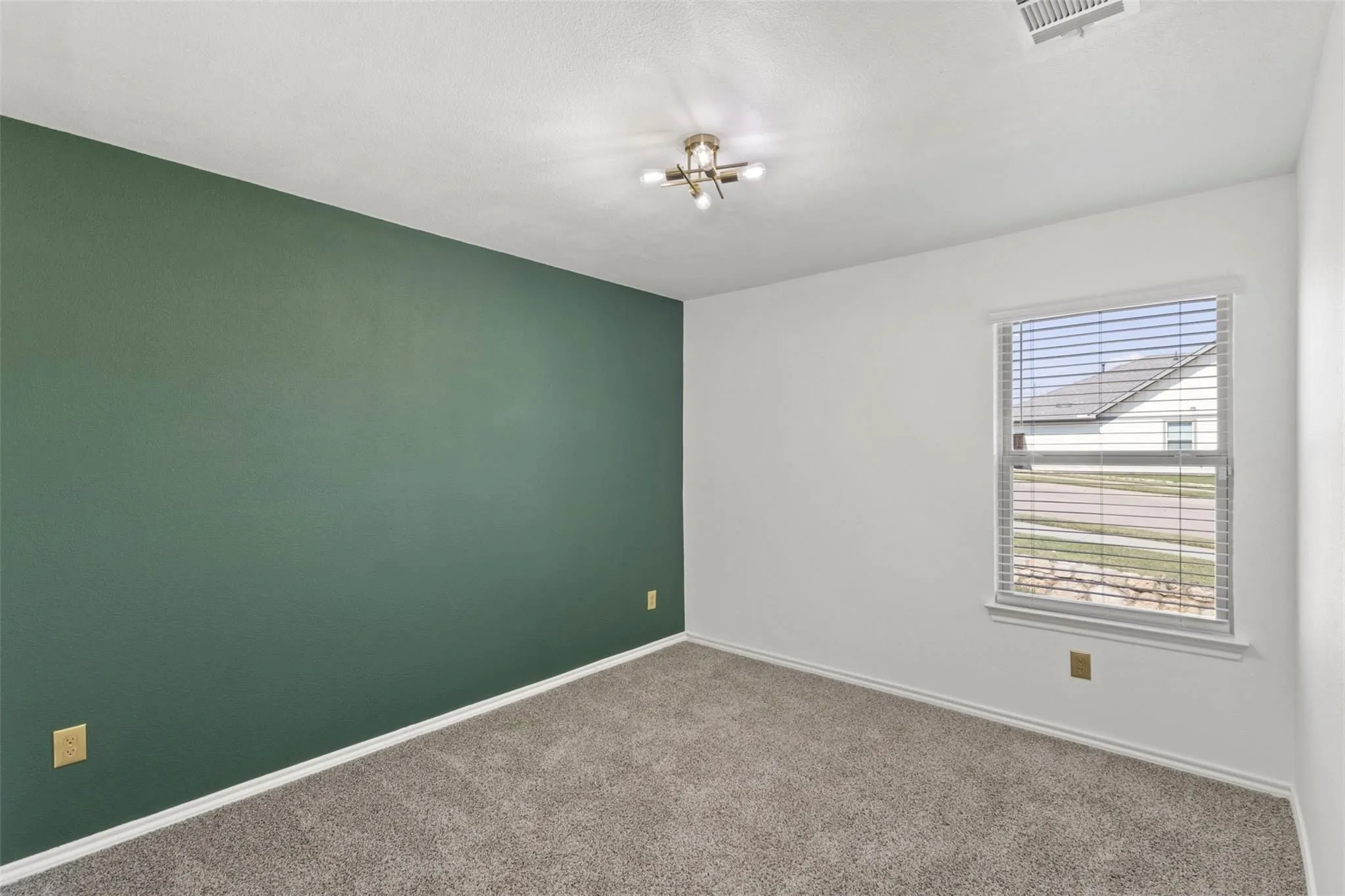Wall-to-wall carpeting, single window with blinds, overhead light fixture, and accent wall