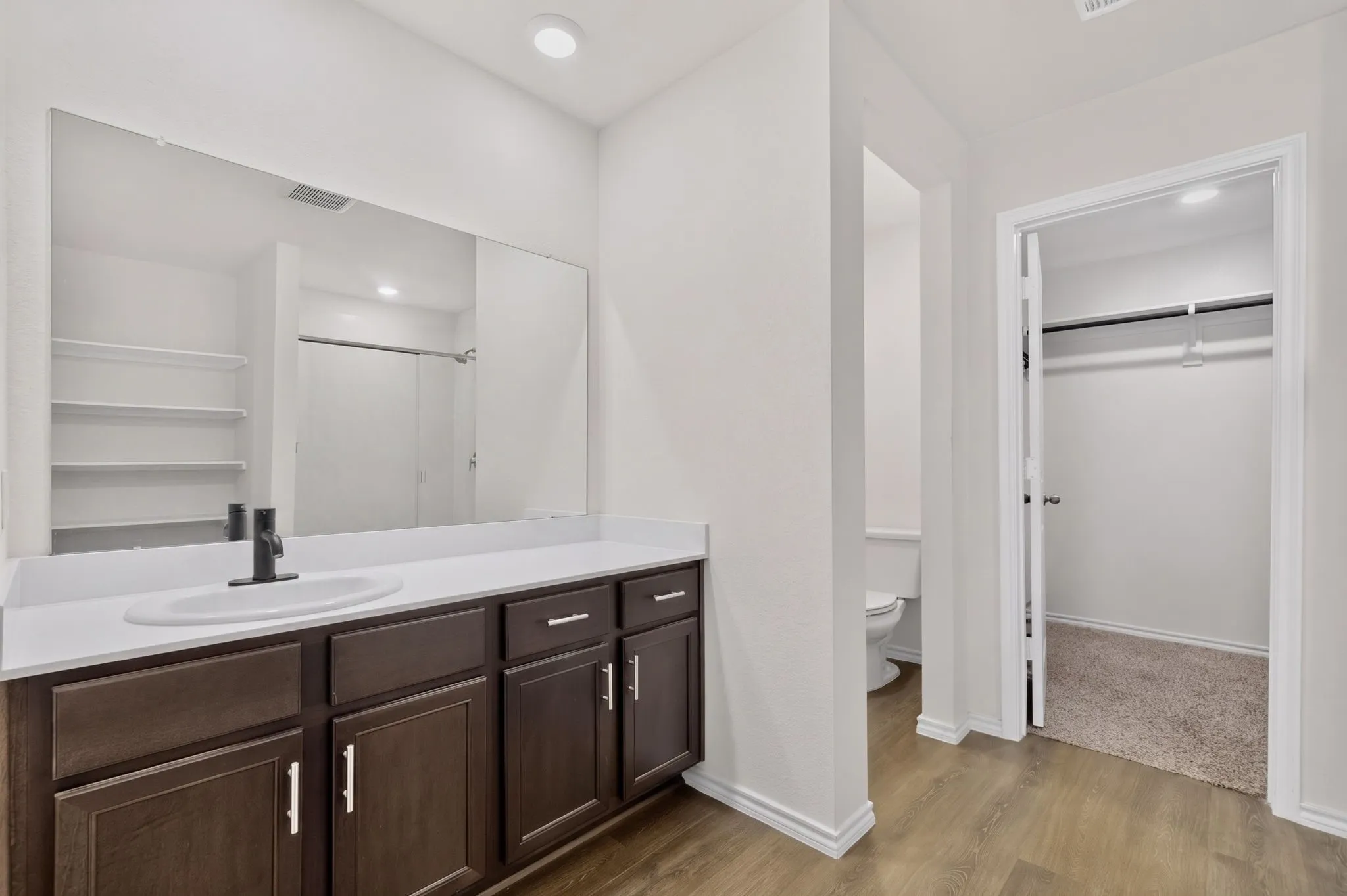 Vanity featuring an integrated sink, dark wood-finish cabinetry, and a large wall-mounted mirror