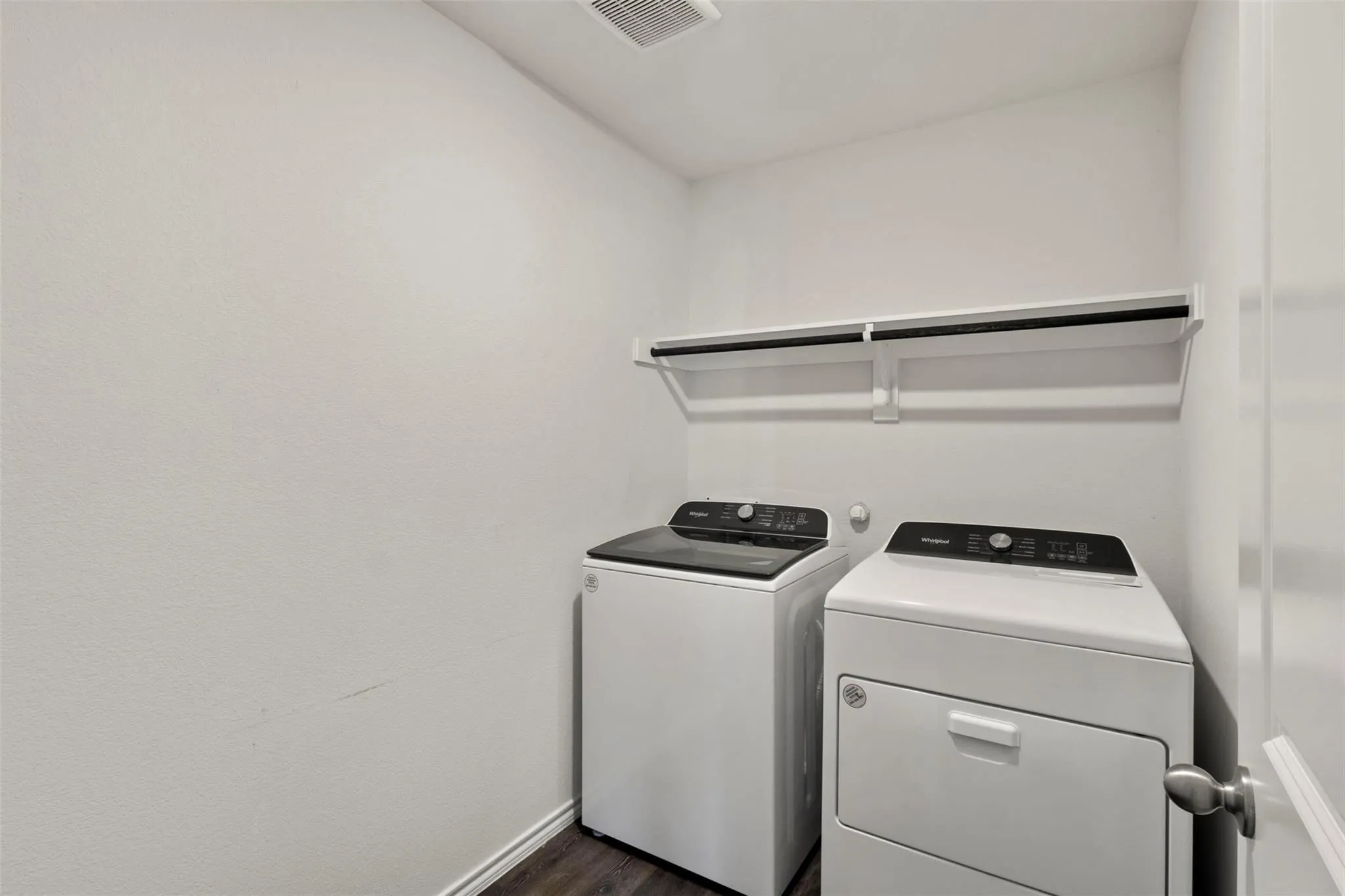 Dedicated laundry area featuring wood-finish flooring and a built-in hanging rod with shelving