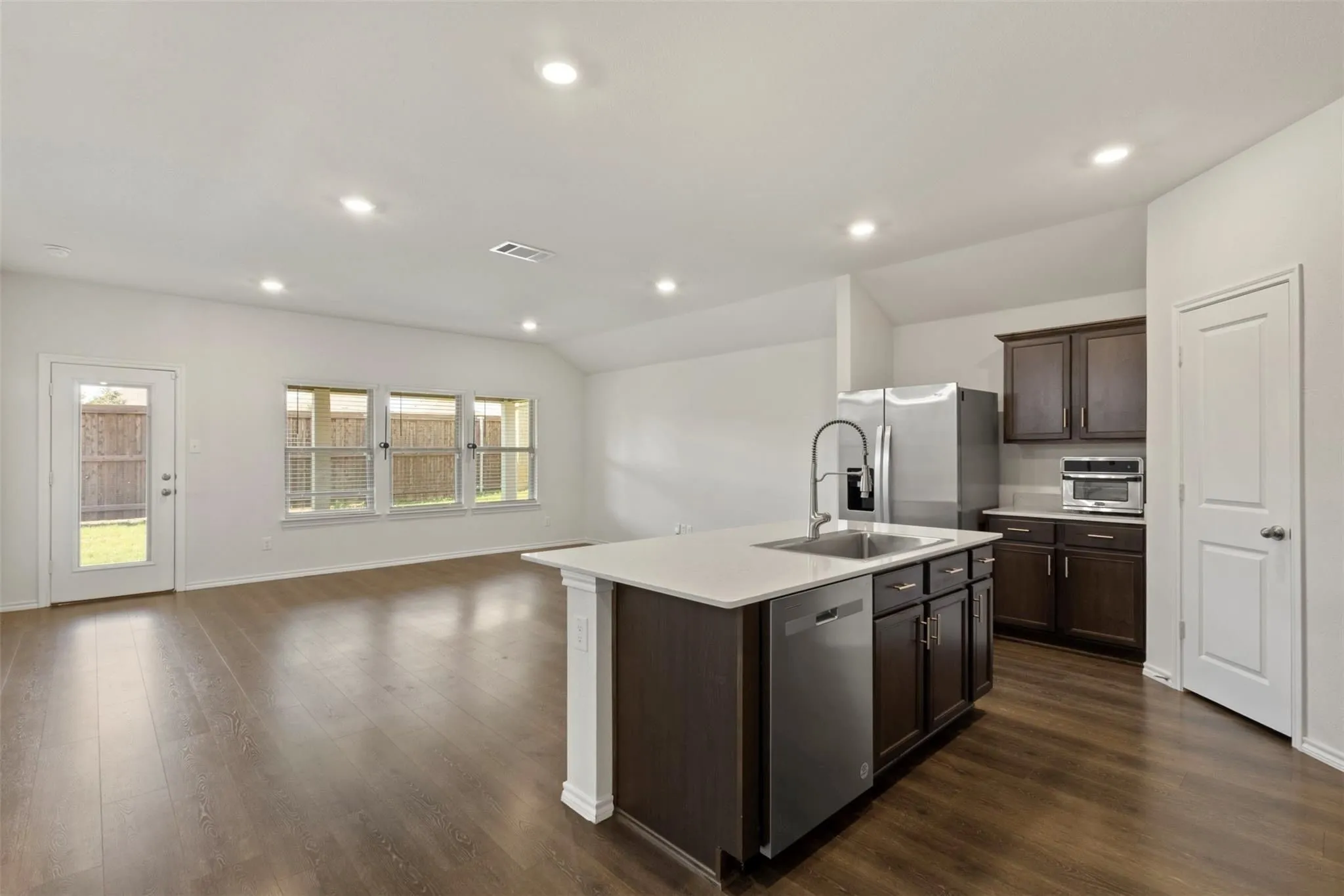 Spacious open-concept area featuring wood-finish flooring, recessed lighting, and ample natural light through multiple windows