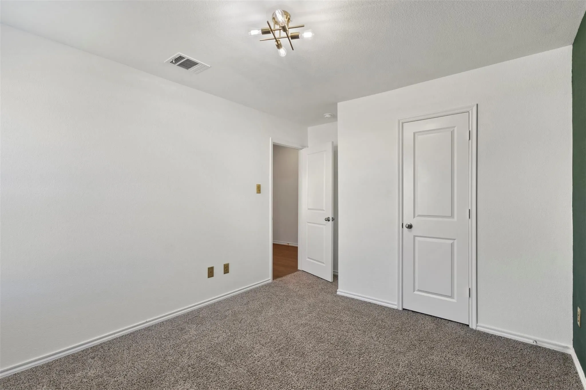 Wall-to-wall carpeting, overhead lighting fixture, and white painted walls