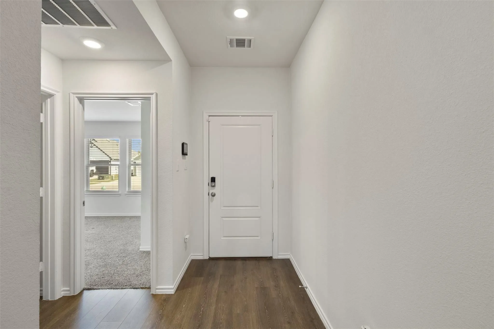 Wood-finish flooring with white trim, recessed lighting, and a paneled entry​​‌​​​​‌​​‌‌​‌‌​​​‌‌​‌​‌​‌​​​‌​​ door