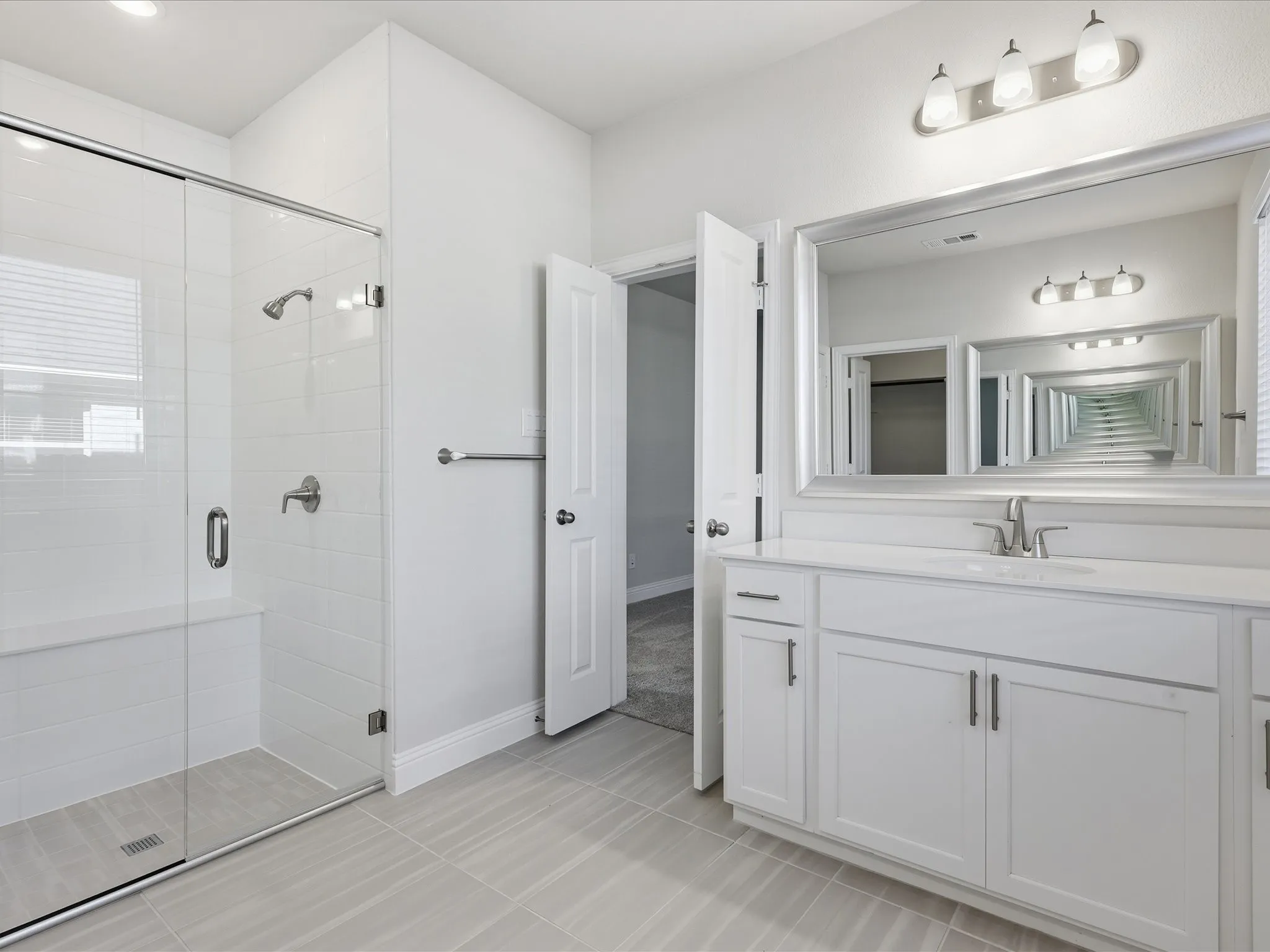 Bathroom with vanity, a stall shower, and light tile patterned floors