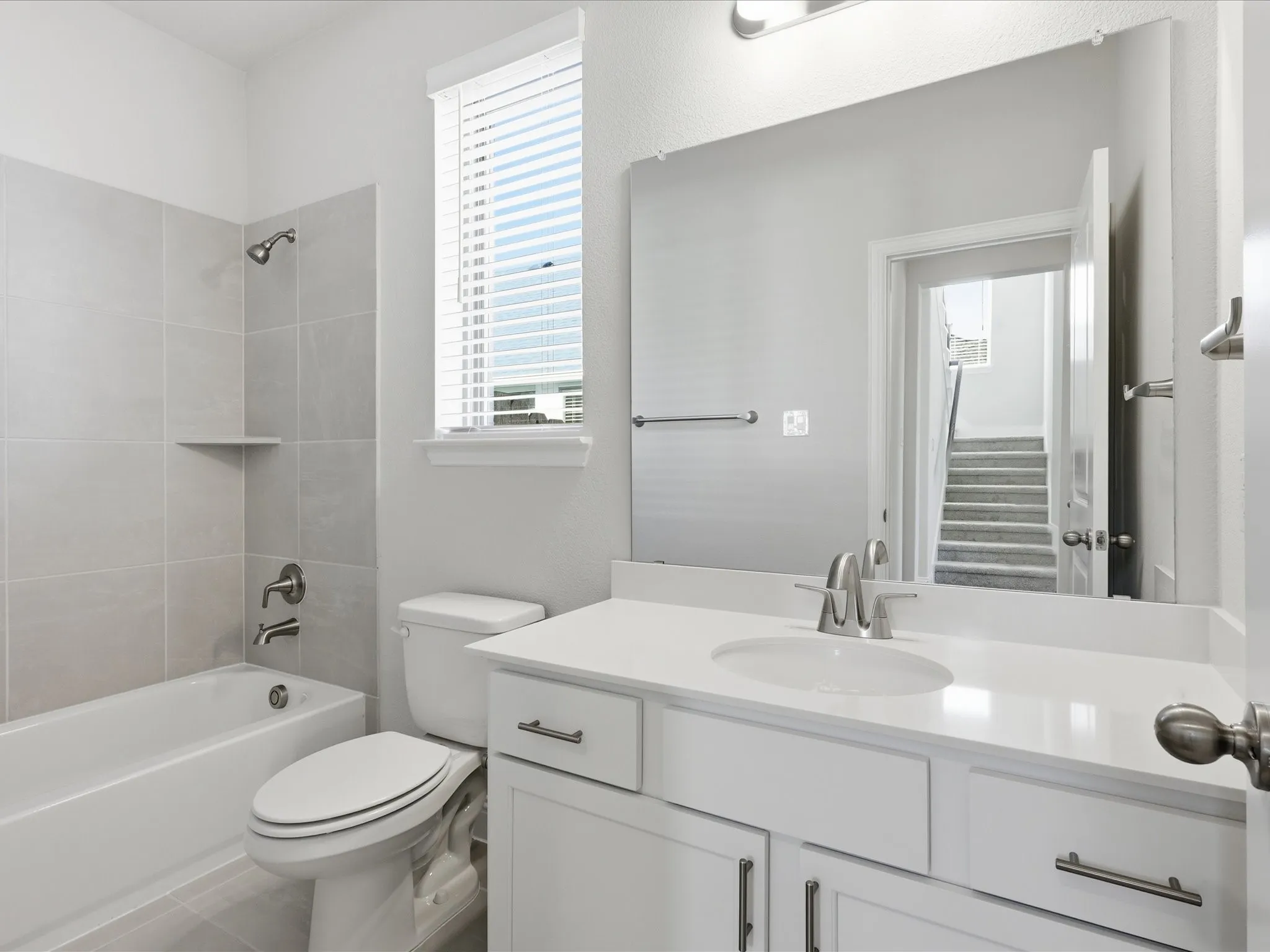 Bathroom with healthy amount of natural light, shower / bath combination, vanity, and tile patterned floors