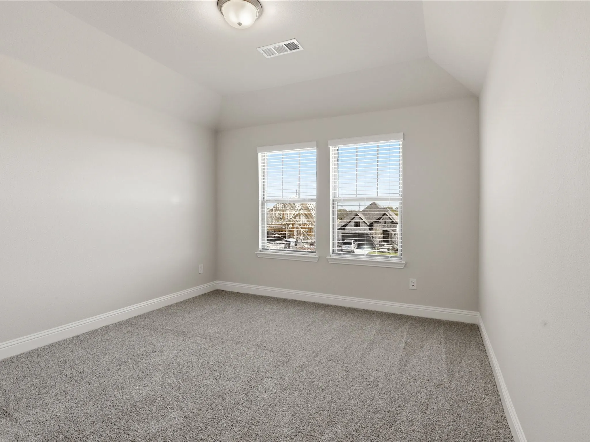 Spare room with vaulted ceiling and light colored carpet