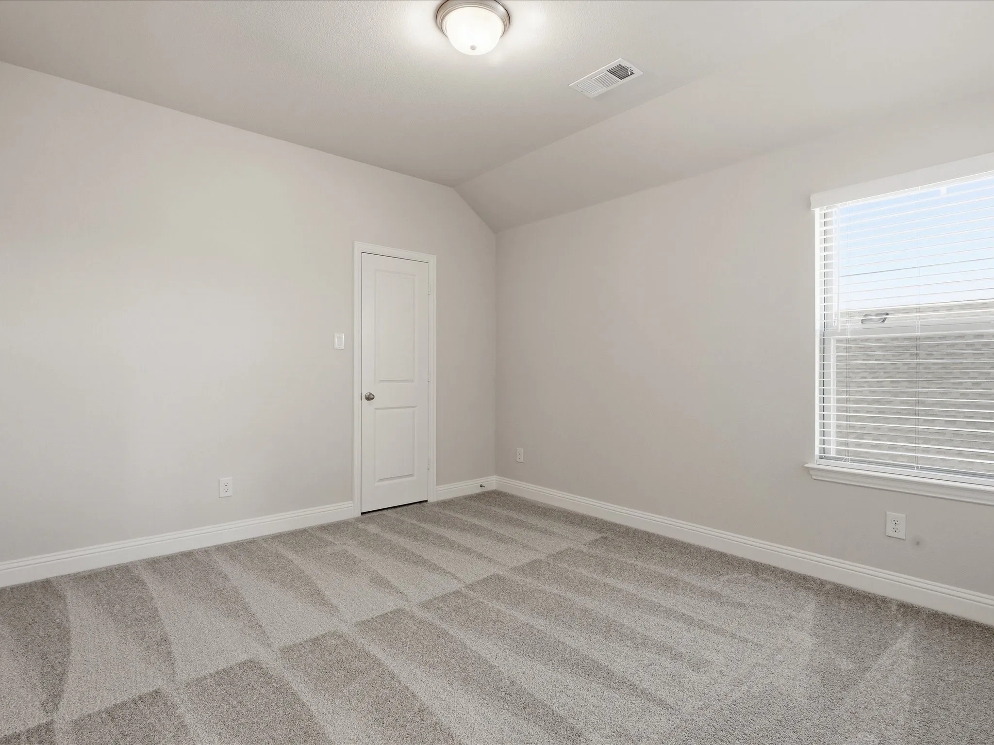 Spare room featuring light colored carpet and lofted ceiling