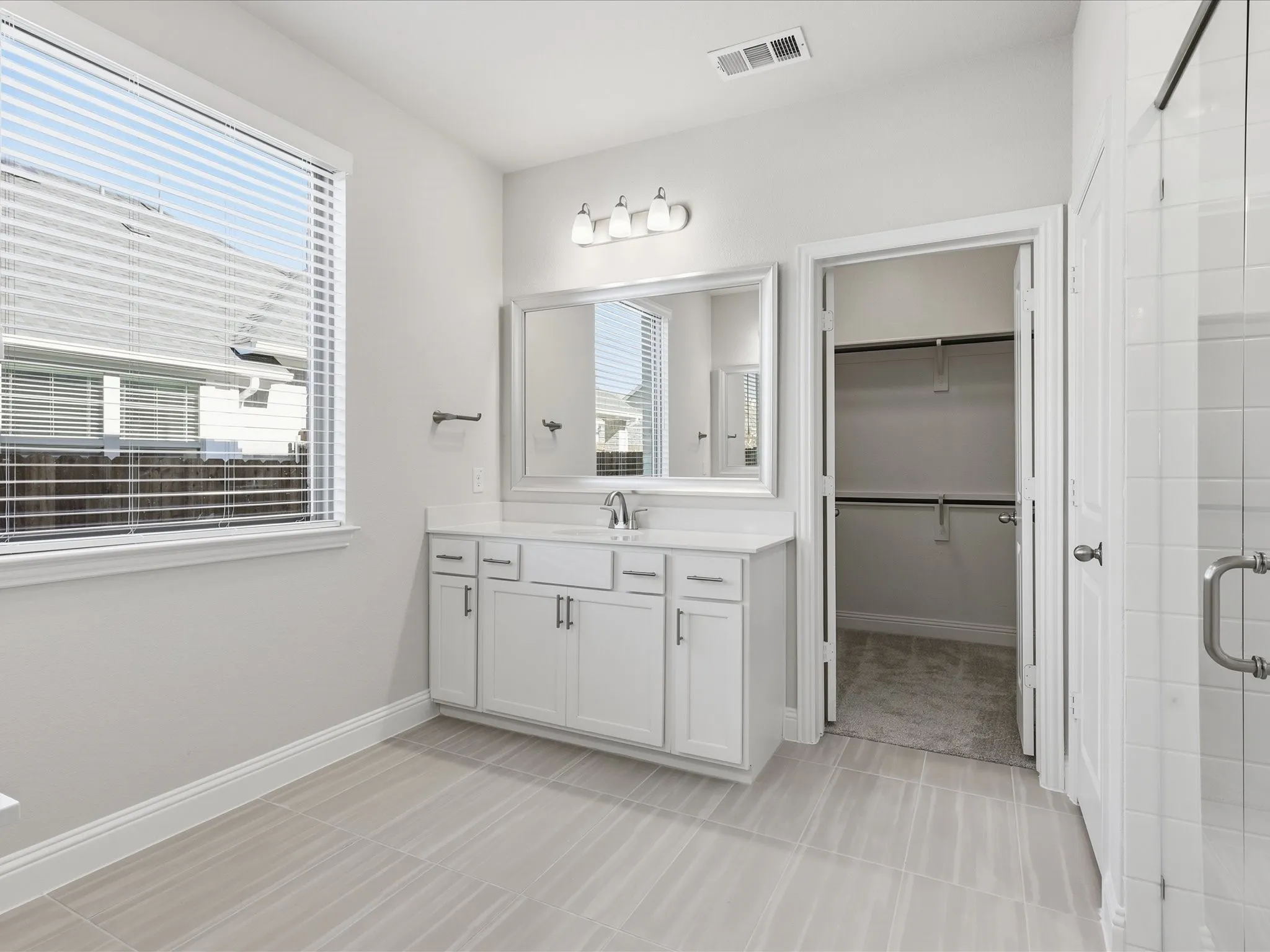 Full bath featuring vanity, a spacious closet, a stall shower, and light tile patterned floors