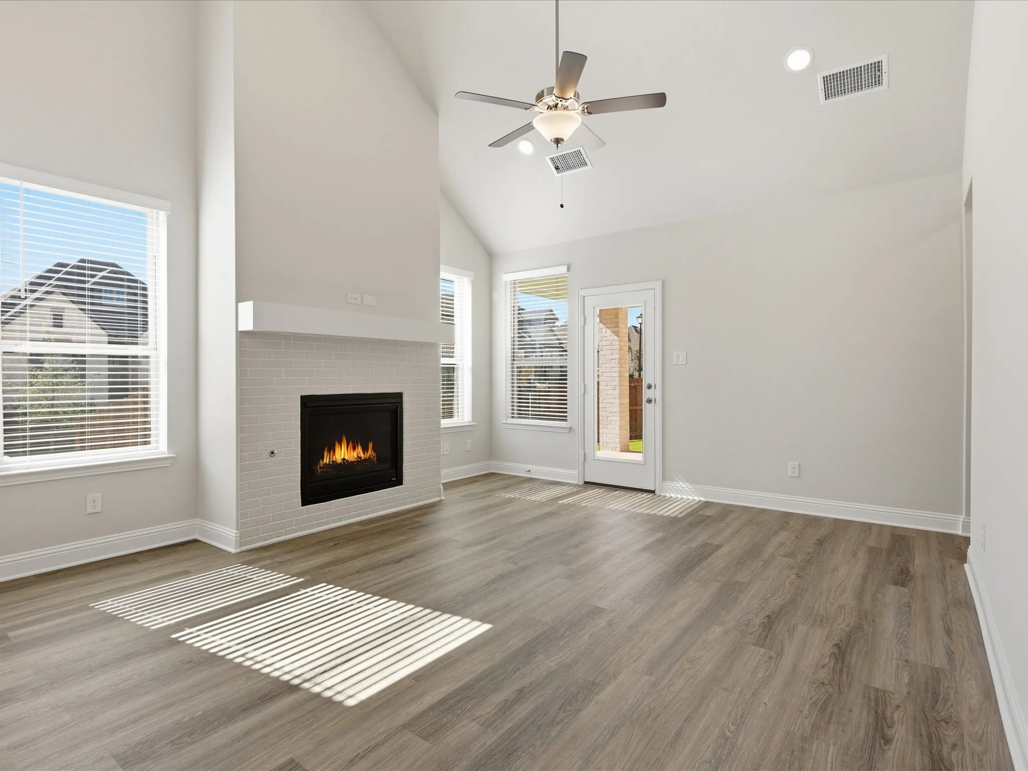 Unfurnished living room featuring high vaulted ceiling, a fireplace, wood finished floors, a ceiling fan, and recessed lighting