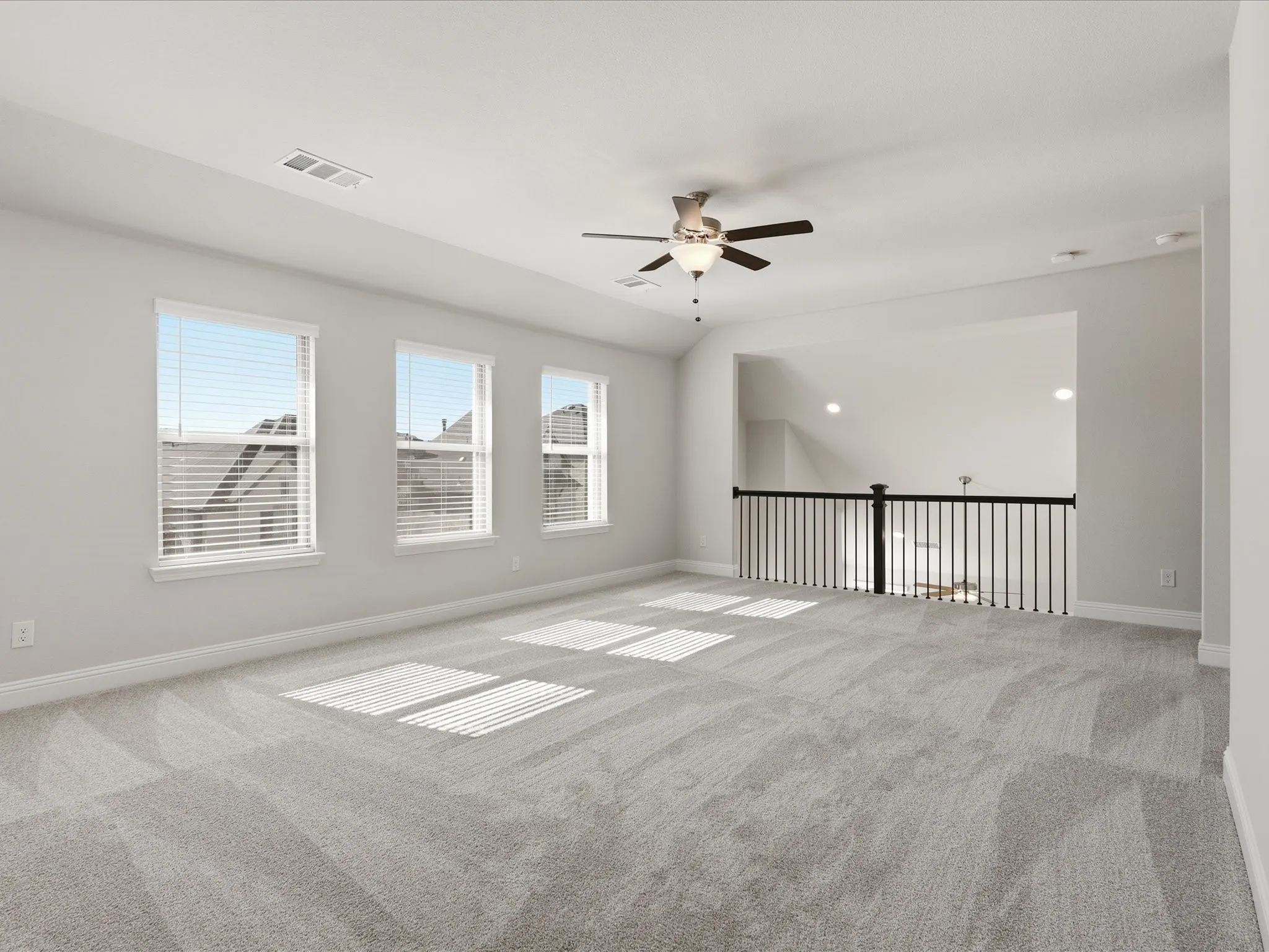 Carpeted empty room featuring a ceiling fan and vaulted ceiling