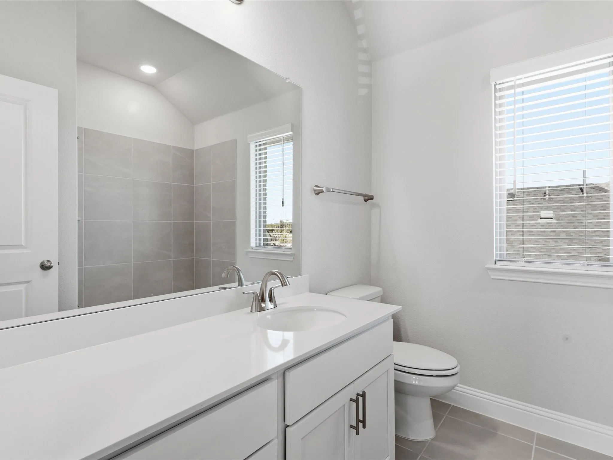 Bathroom featuring light tile patterned floors, vanity, lofted ceiling, and recessed lighting