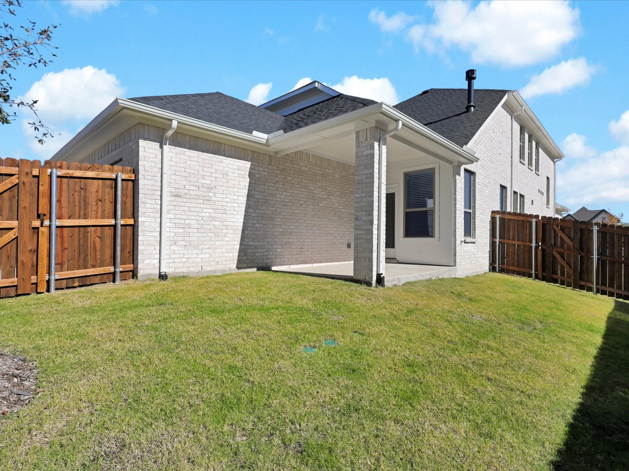 Rear view of house featuring a gate, a patio area, and brick siding