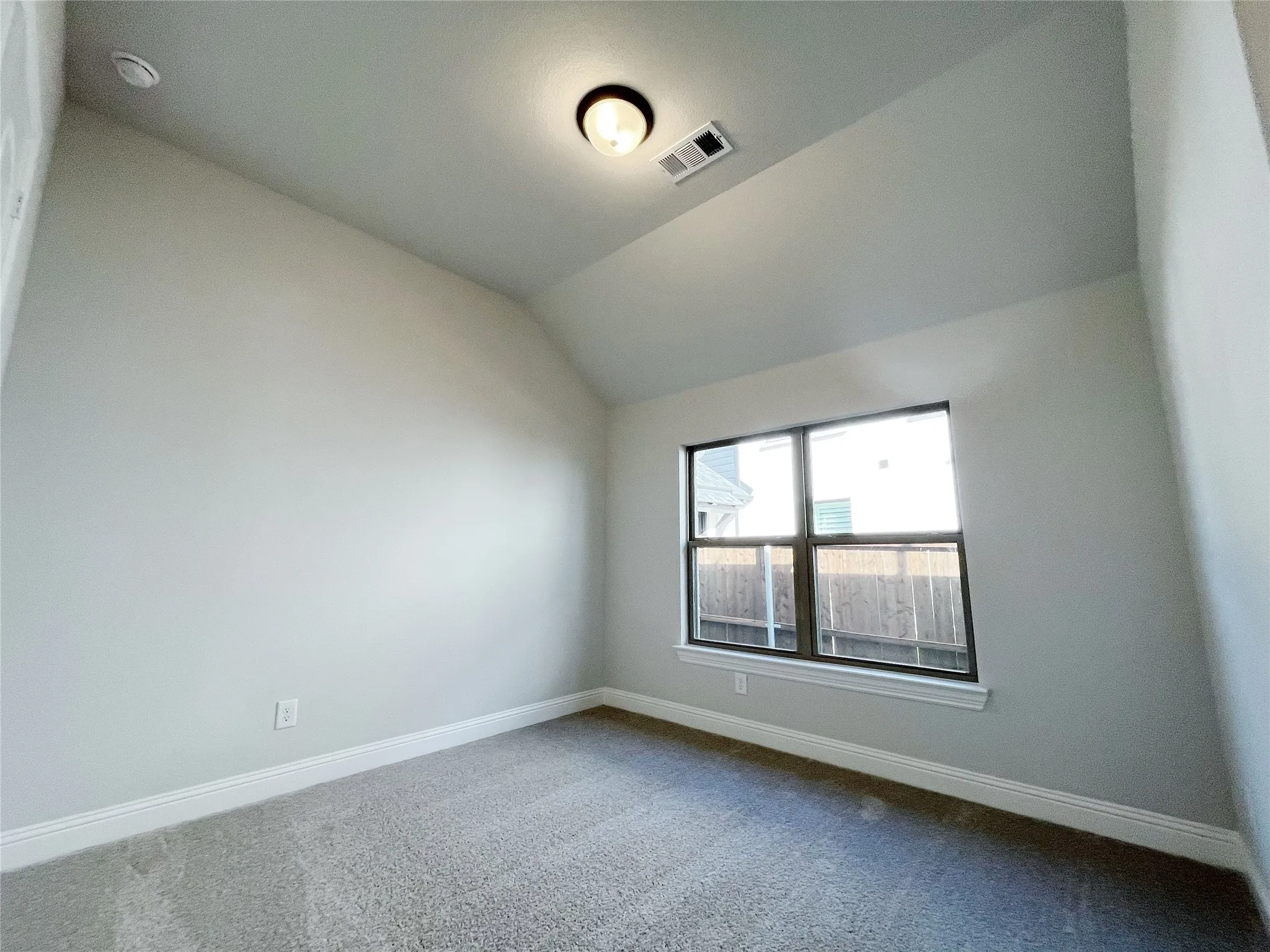 Vaulted ceiling, recessed lighting, double-pane window, neutral carpet, and light-colored walls