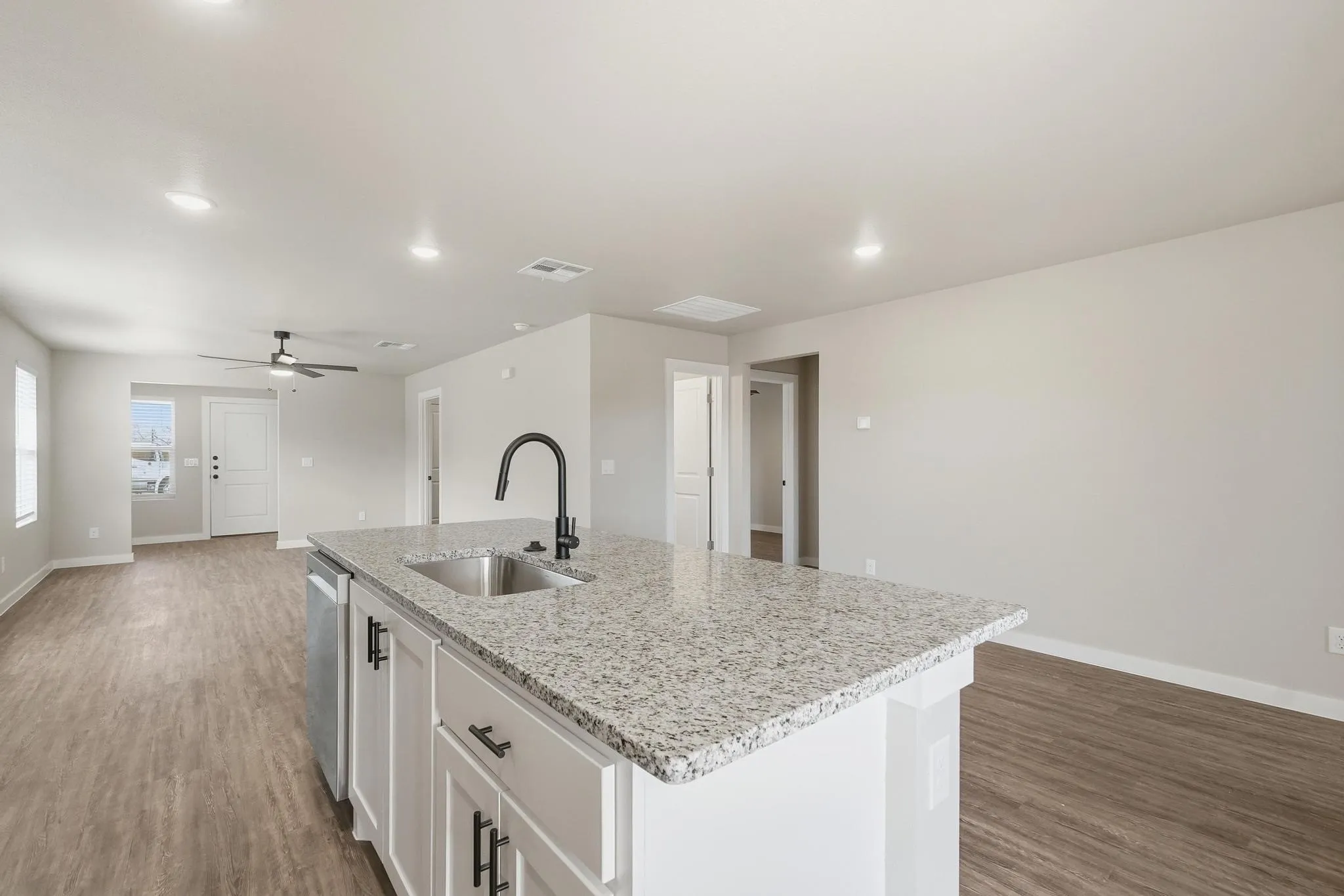 Kitchen island featuring a stainless steel sink, black gooseneck faucet, and light-toned stone countertop