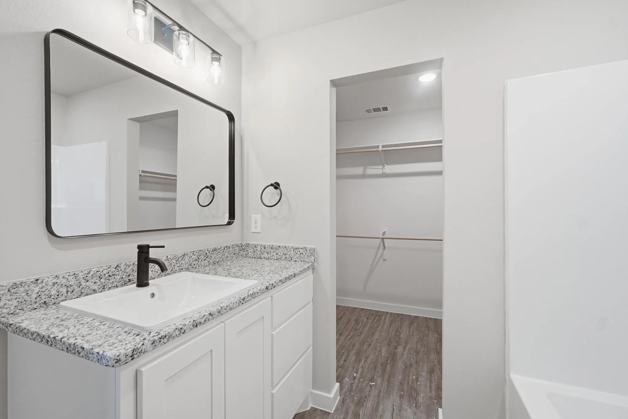 White vanity with a light granite countertop, undermount sink, and matte black faucet