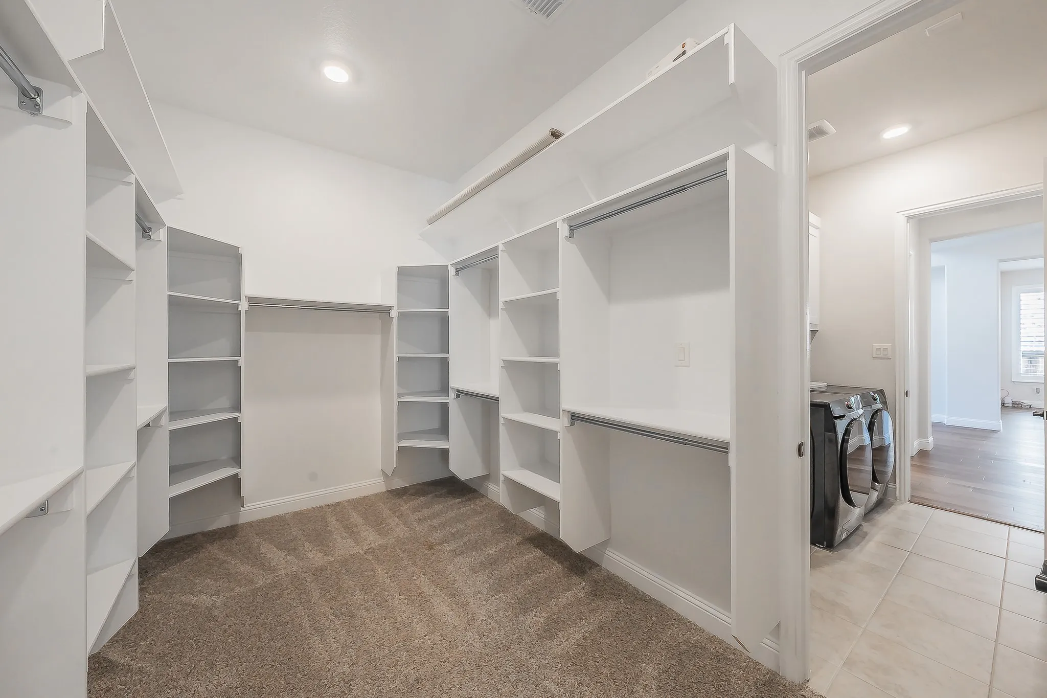 Integrated closet system with extensive shelving, hanging rods, and carpet flooring