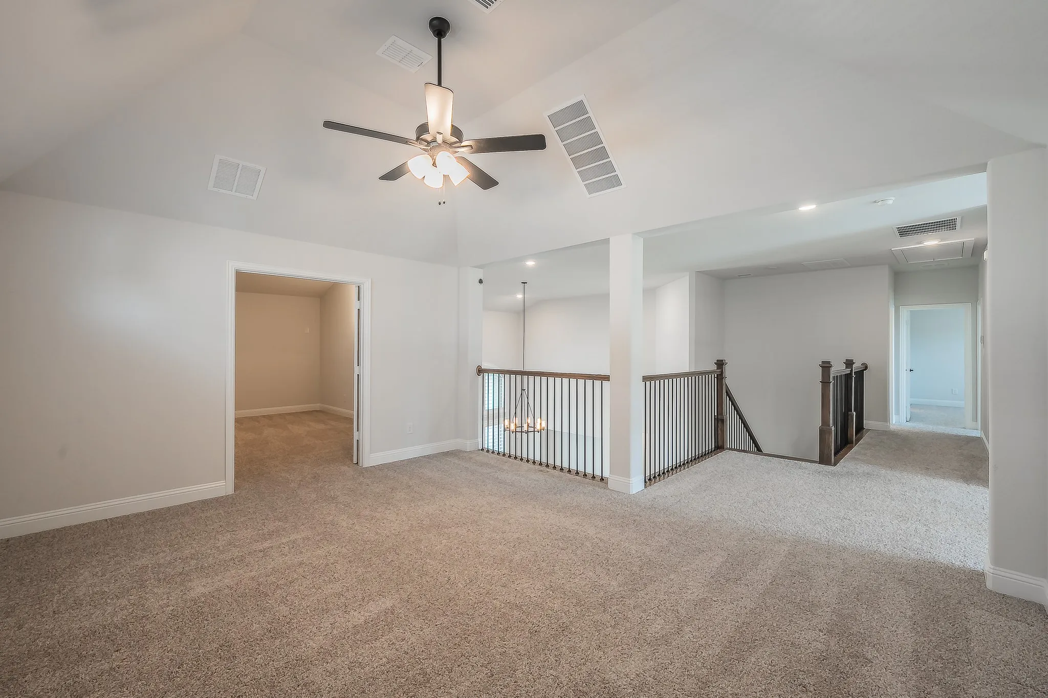 Carpeted bonus/ gameroom with a vaulted ceiling, ceiling fan, recessed lighting, and a wood and metal baluster railing