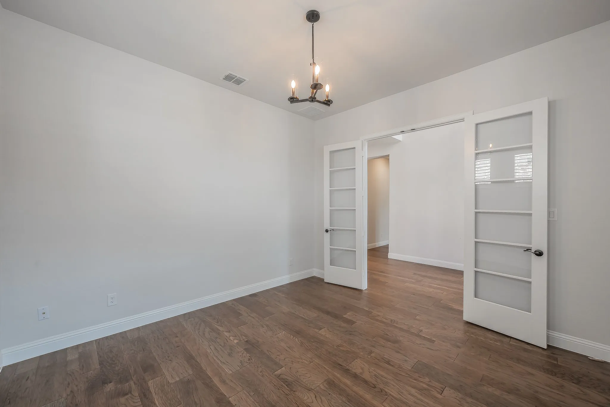 Wood-finish flooring, white walls, and a contemporary chandelier
