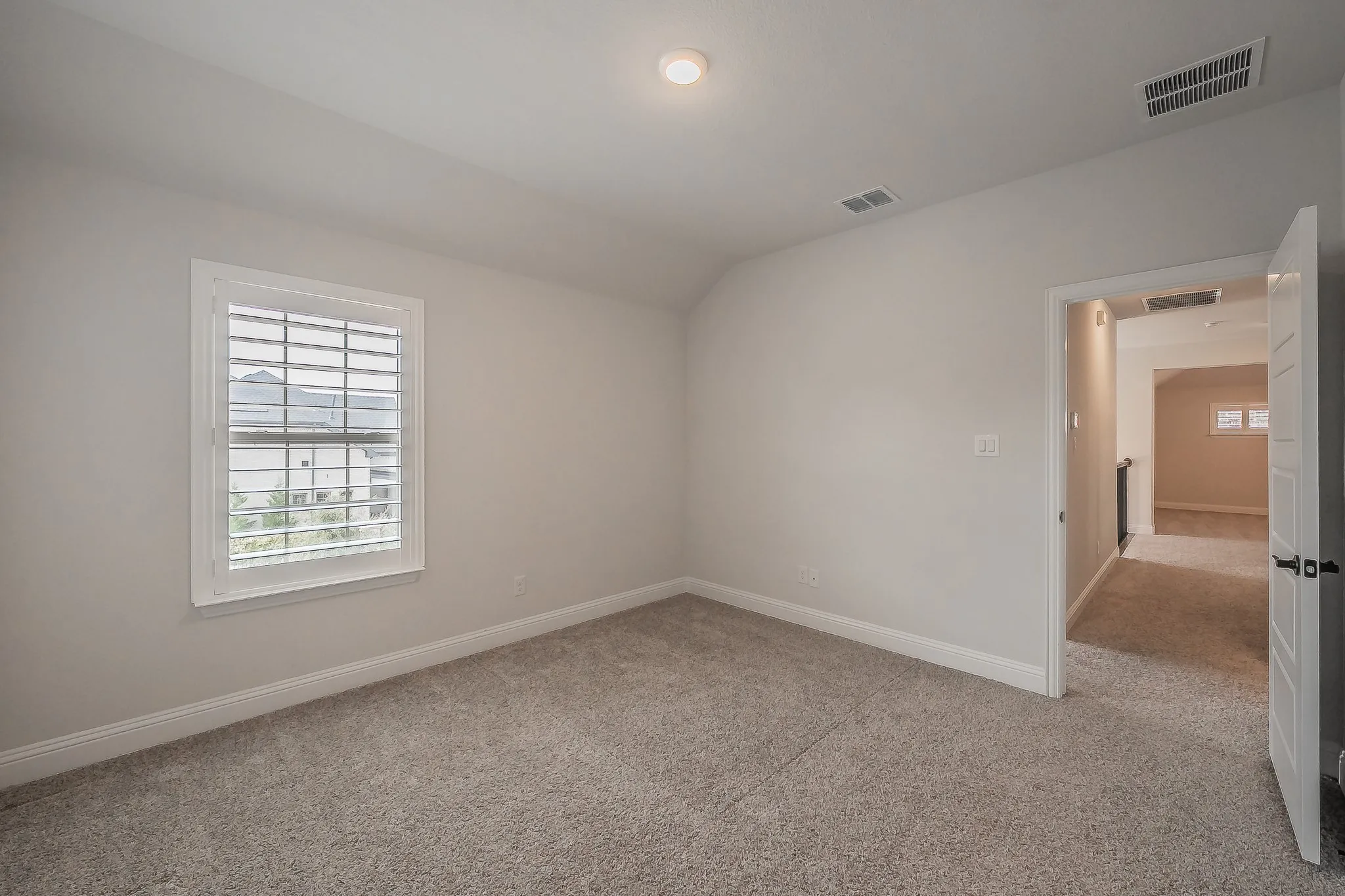 Recessed ceiling light, neutral wall paint, carpeted flooring, and white window shutters