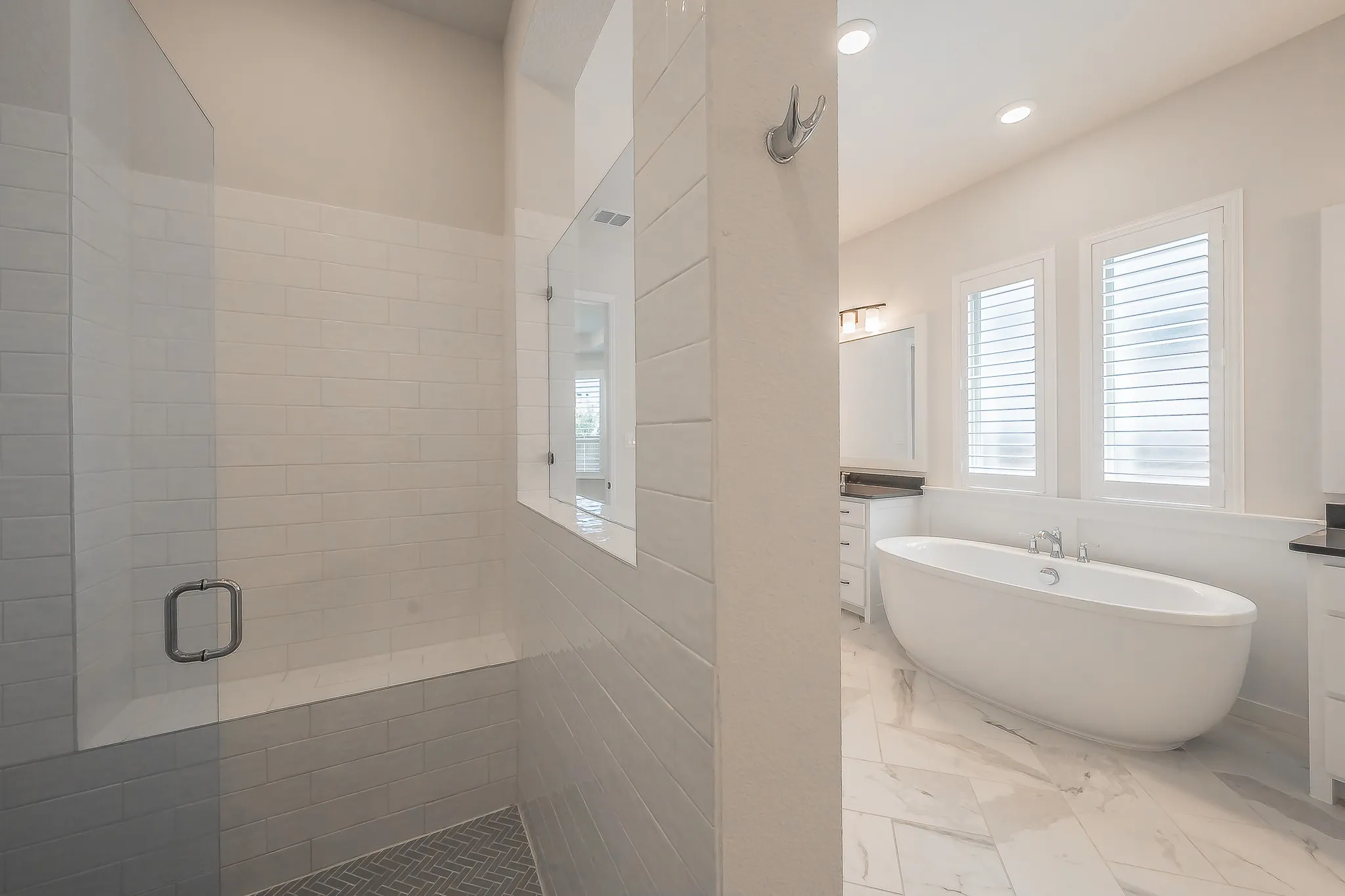 Walk-in shower with a glass enclosure, an integrated bench, and a herringbone tile floor