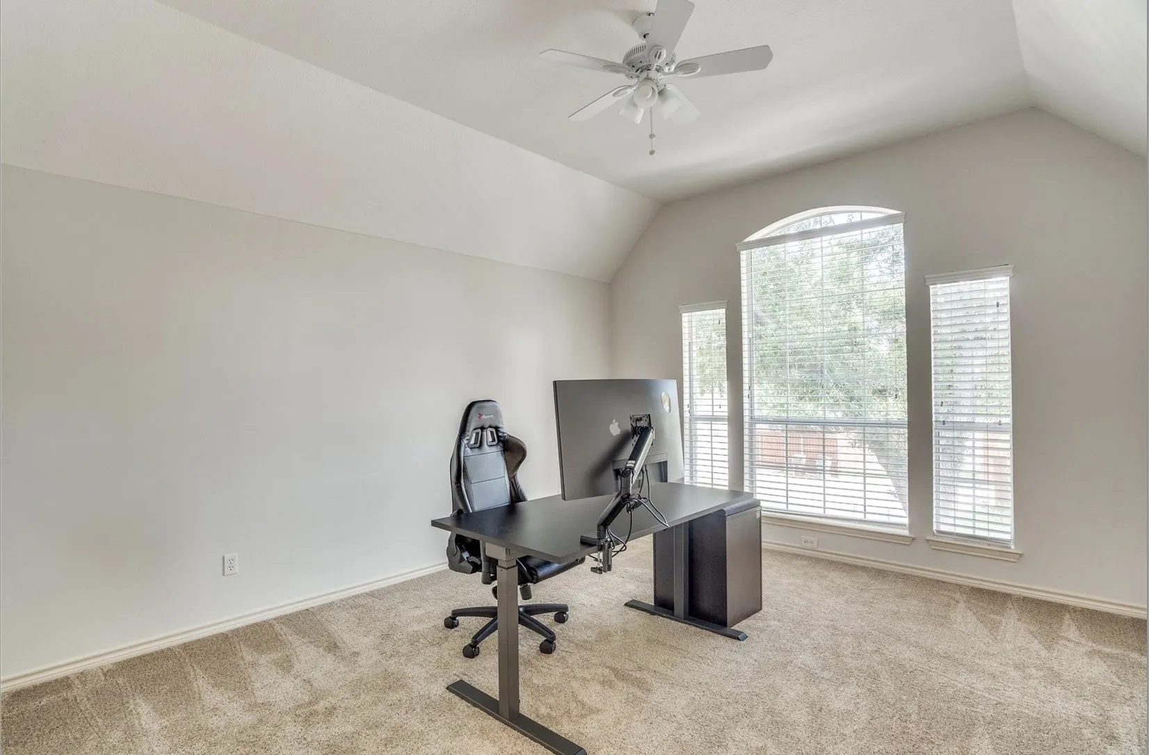 Vaulted ceiling with a ceiling fan, arched window, two rectangular windows, and carpet flooring