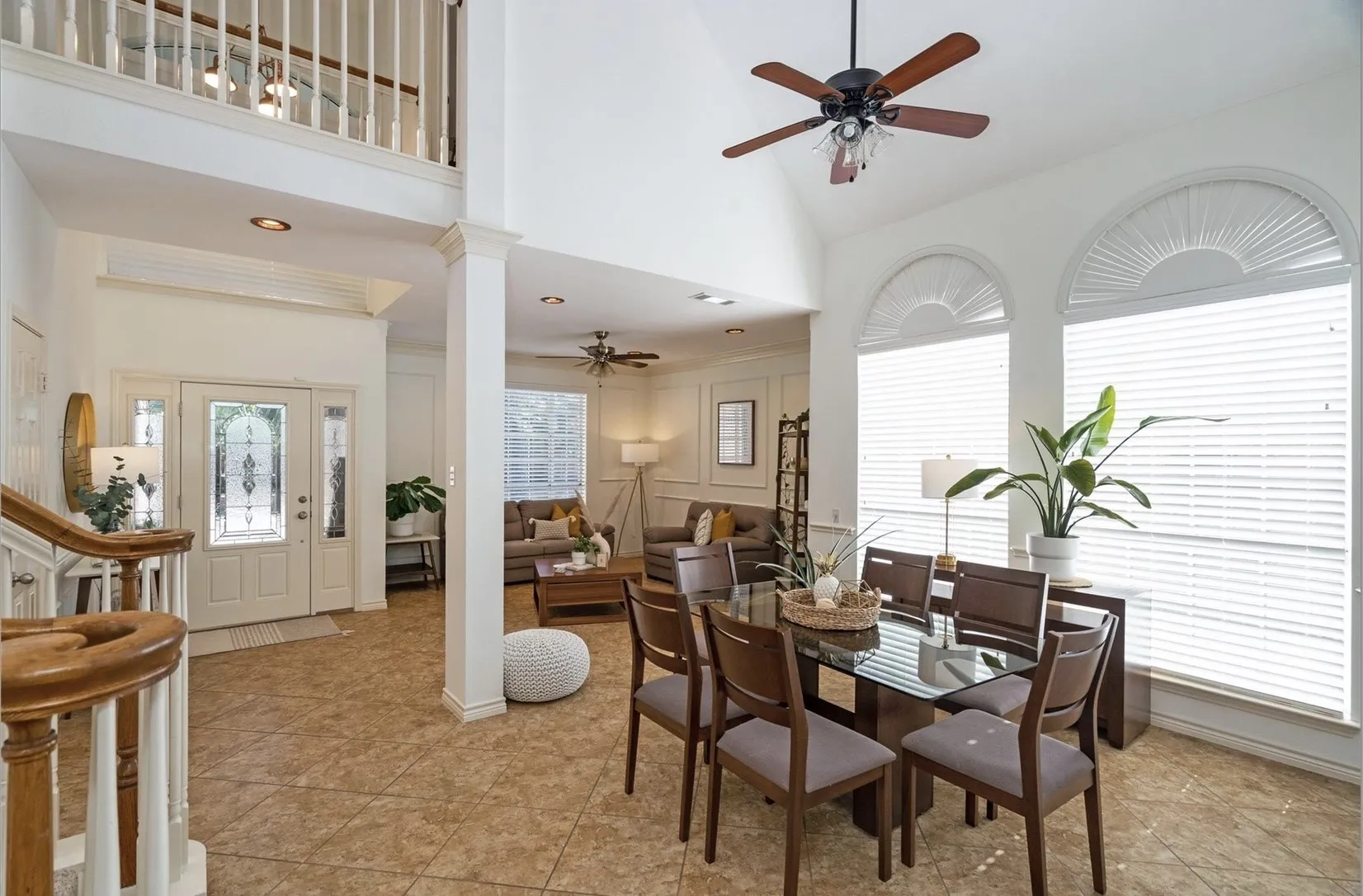 Entryway with tile flooring, a staircase with wood handrails, and a soaring two-story ceiling