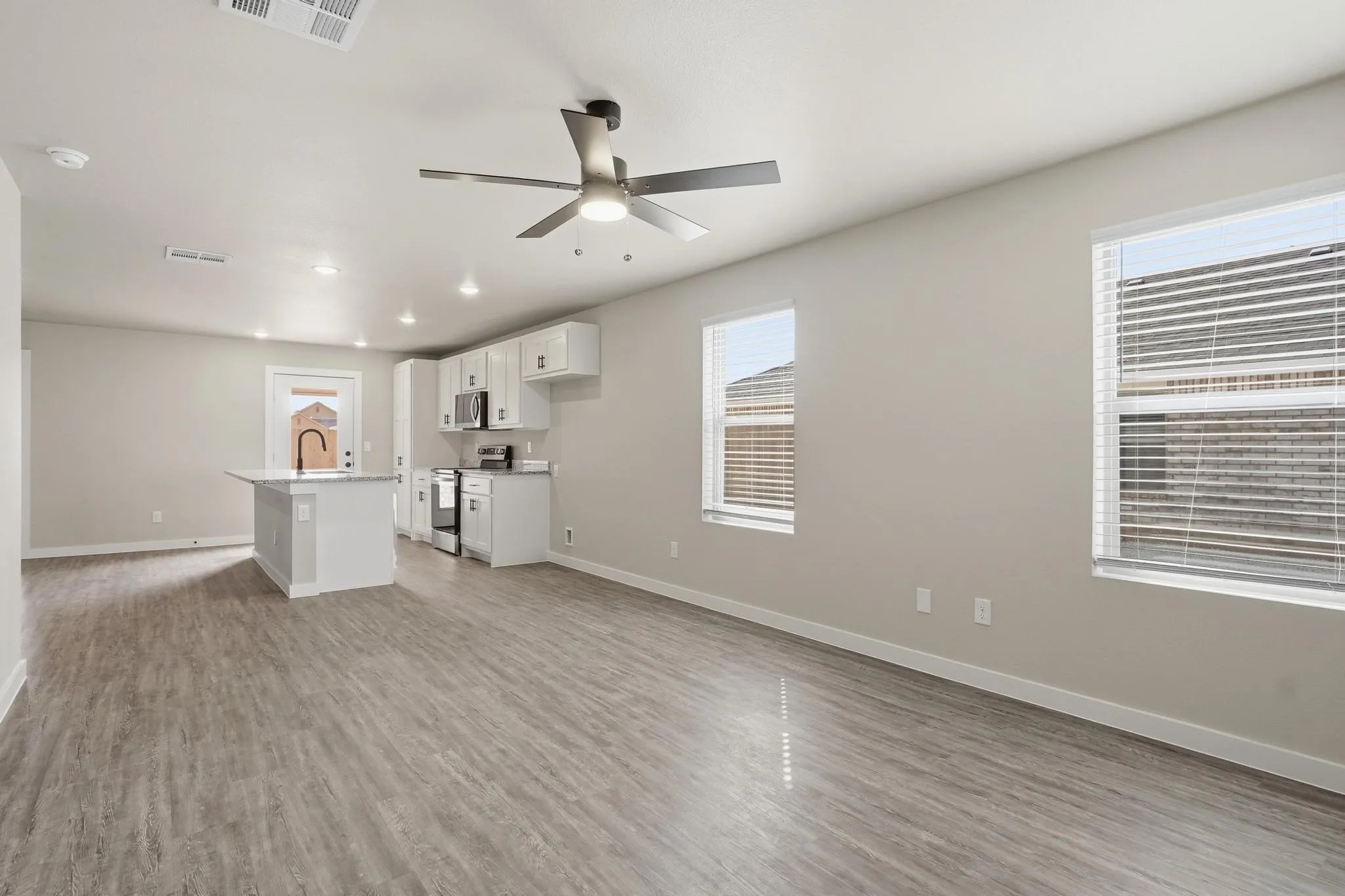 Open-concept living area with wood-finish flooring, recessed lighting, and a ceiling fan
