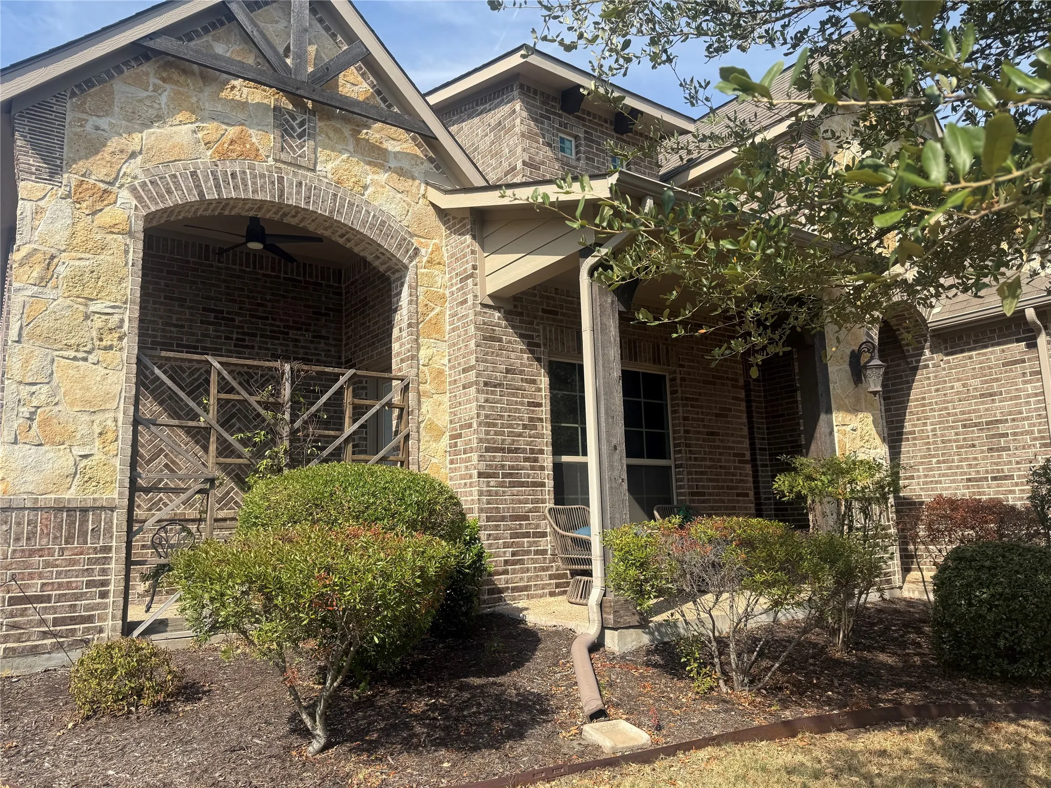 Brick and stone exterior with arched entryway, covered porch, and exterior lighting