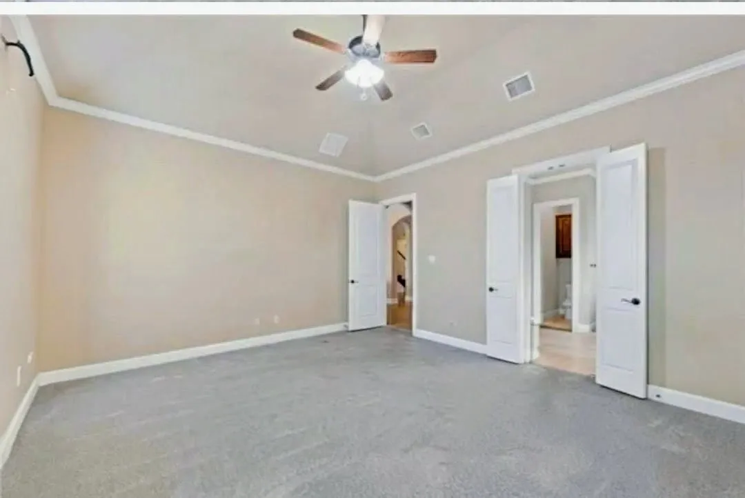 Carpeted room featuring a ceiling fan, crown molding, and two sets of double doors