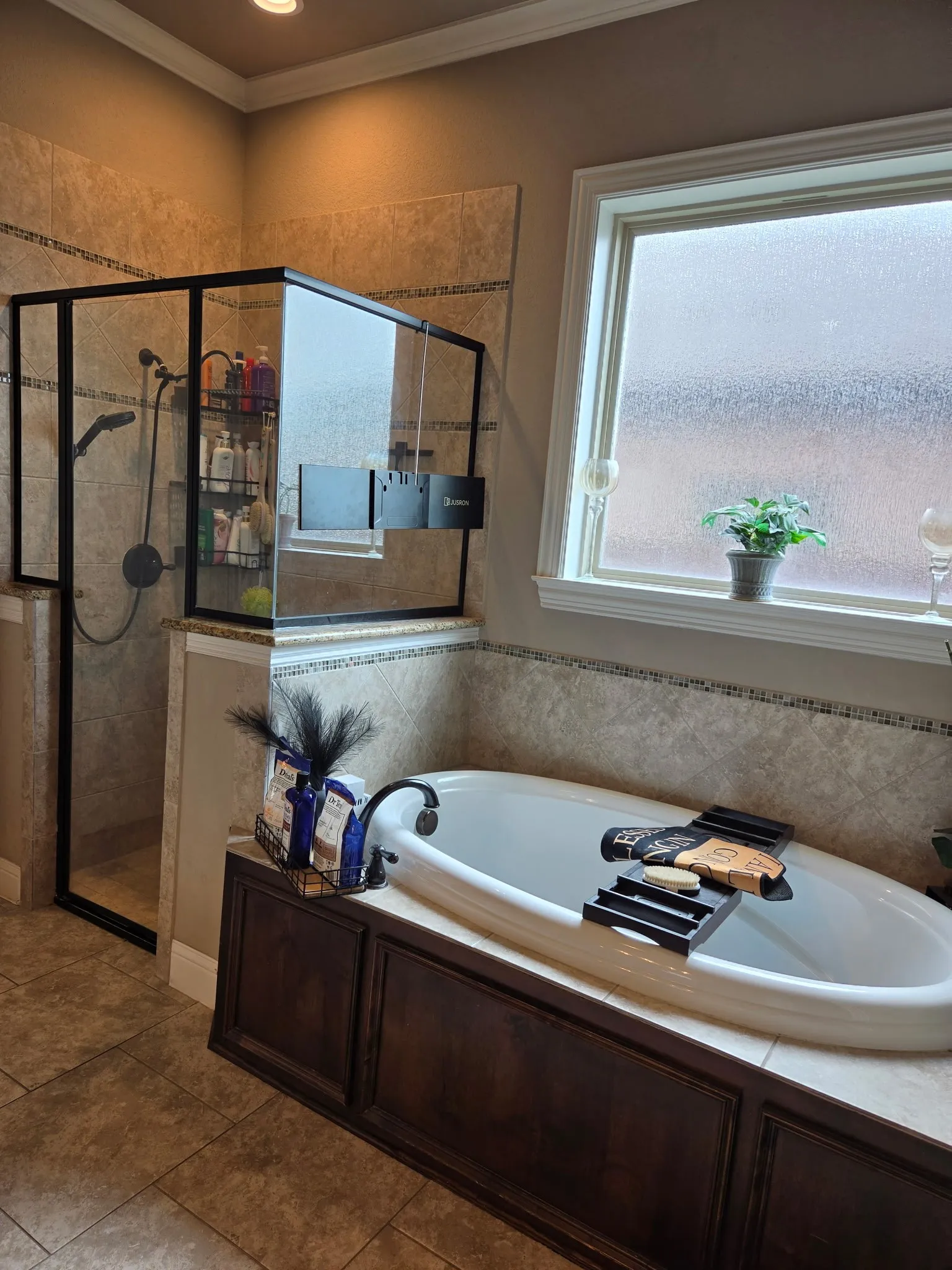 Built-in soaking tub with dark wood paneling, a large frosted window, and an adjacent glass-enclosed shower with tile surround