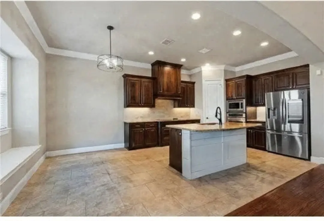 Kitchen featuring dark wood cabinetry, a central island with a light-toned countertop, stainless steel appliances, and recessed lighting