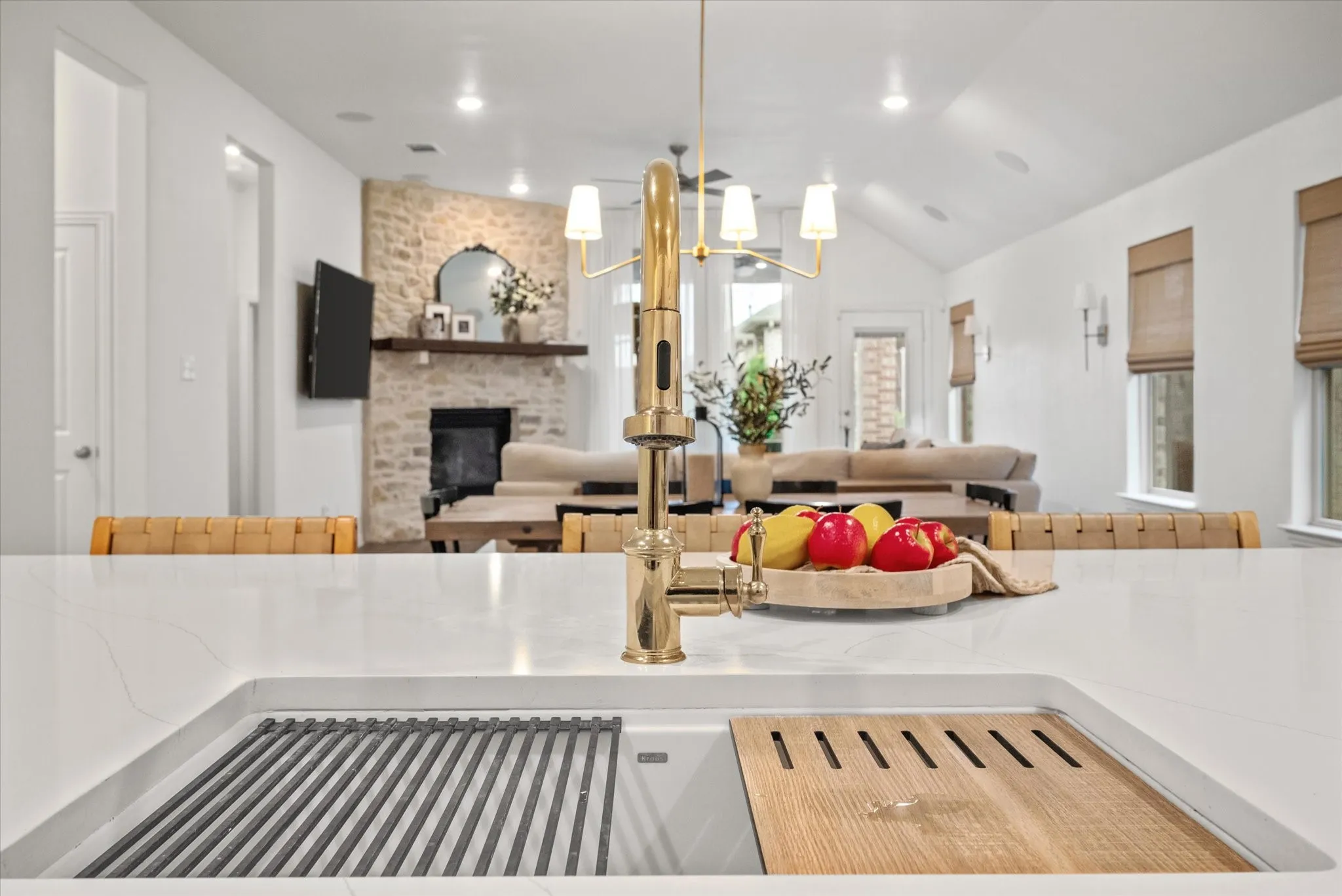 Integrated kitchen sink with a gold-tone faucet, a stone fireplace, and vaulted ceilings