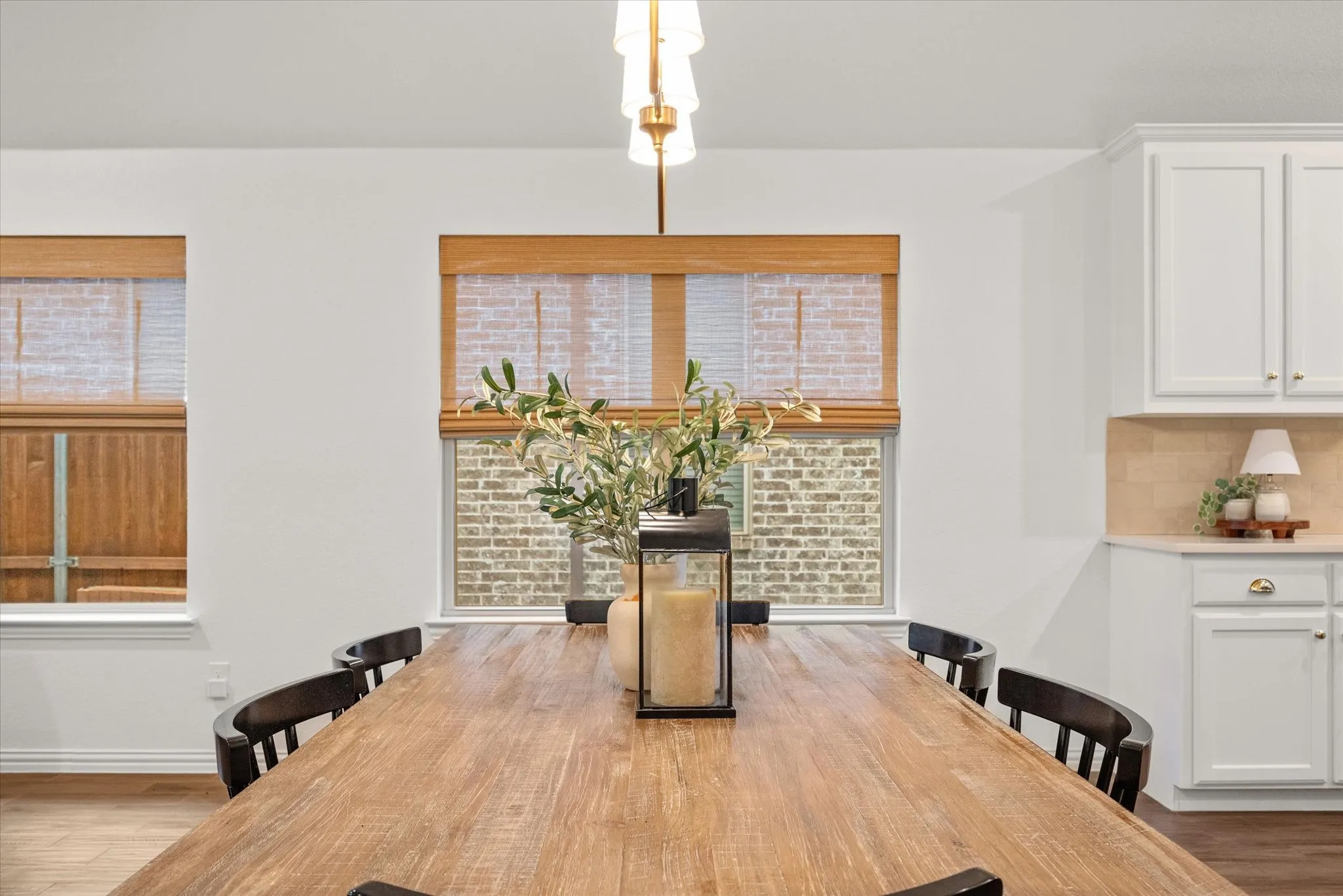 Hardwood flooring with a matte finish, white shaker-style cabinetry, and light-toned tile backsplash