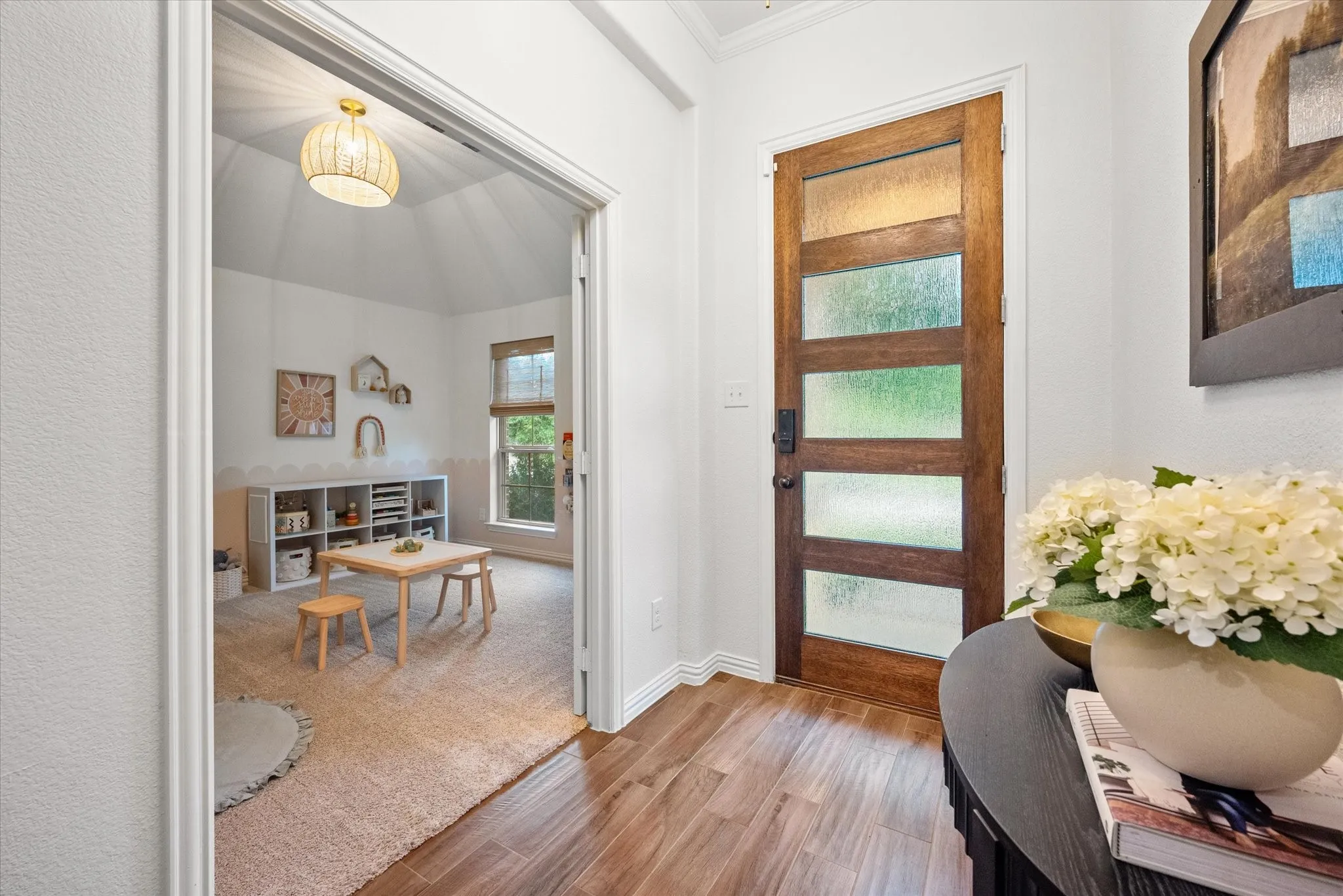 Wood-finish flooring leading to a wood entry door with frosted glass panels