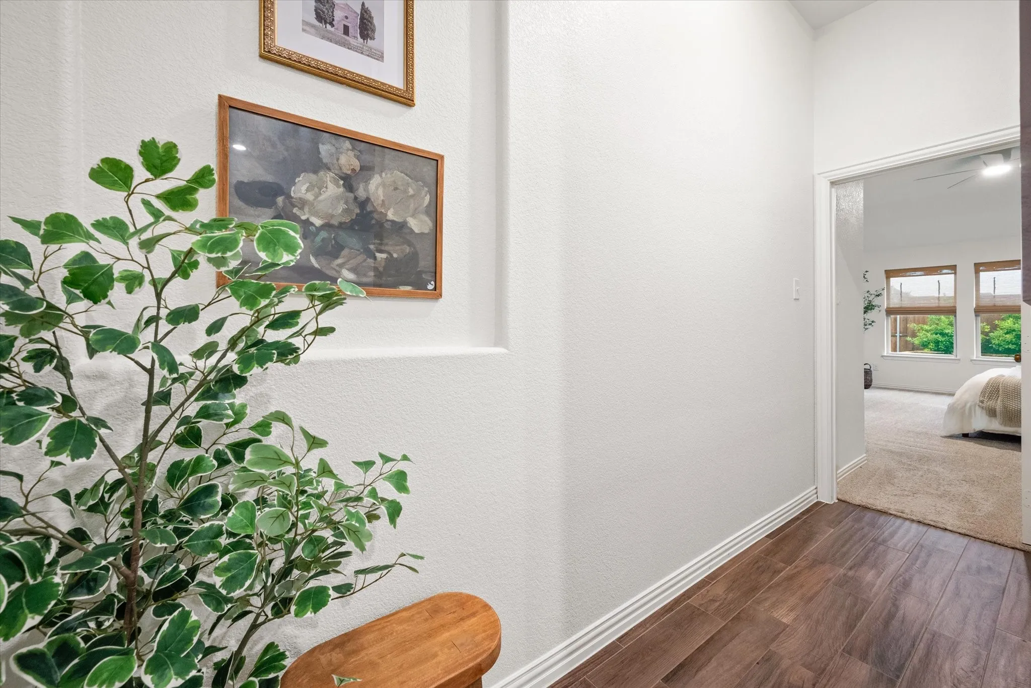 Wood-finish flooring extending into the hallway, white painted walls, and white trim
