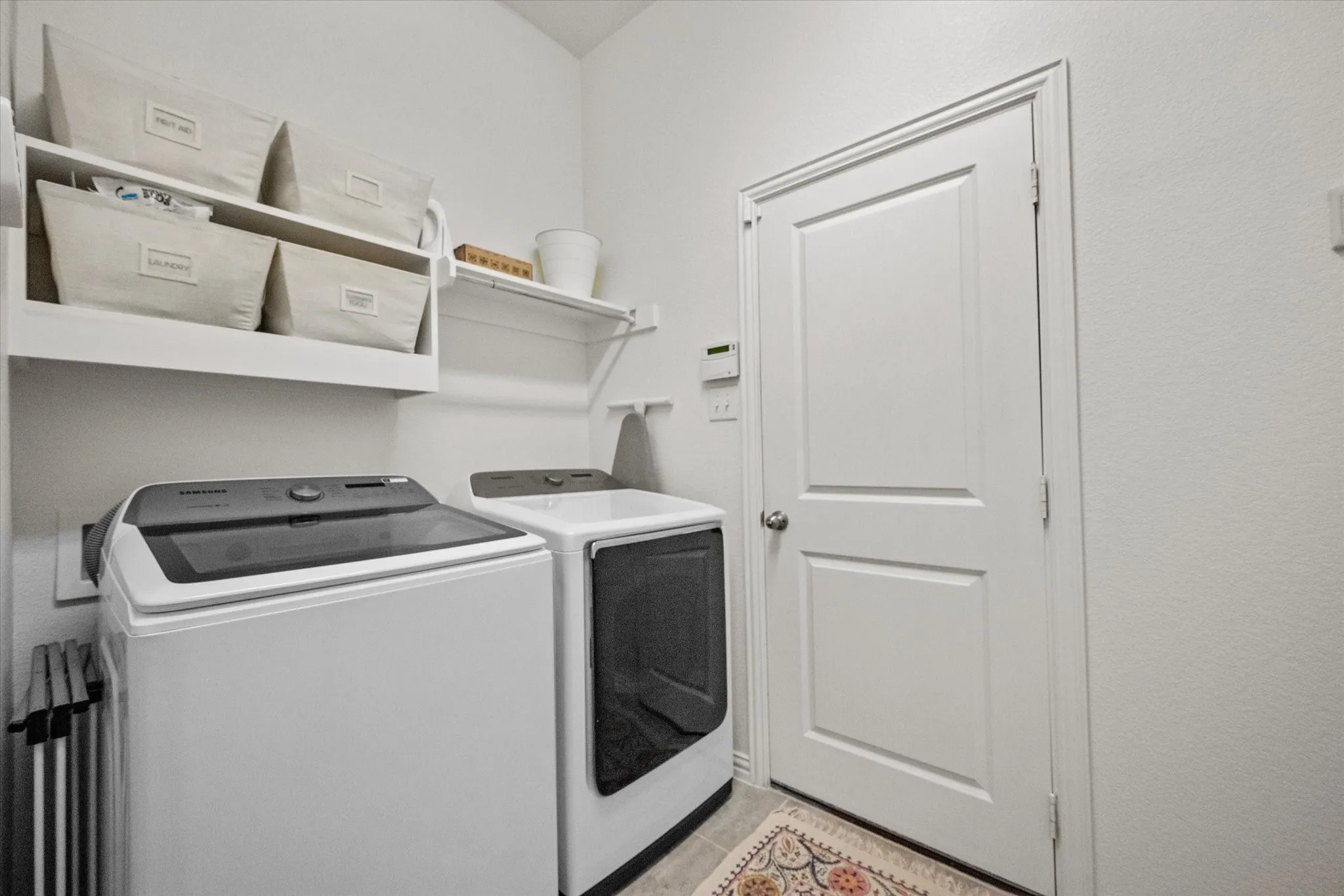 Laundry area featuring wall-mounted shelving, a closed door with a knob handle, and textured walls