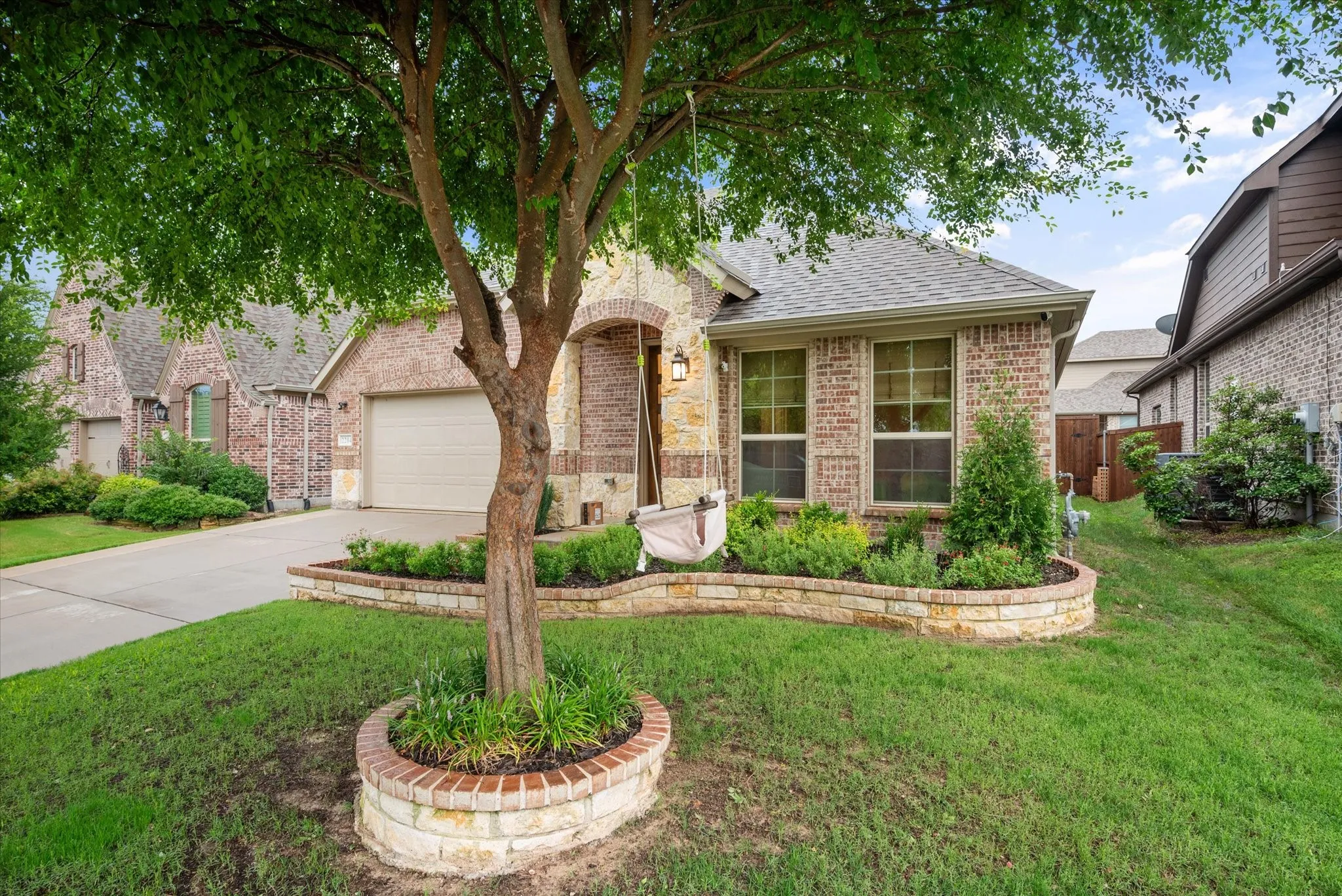Brick exterior with stone accents, a two-car garage, and a covered entry